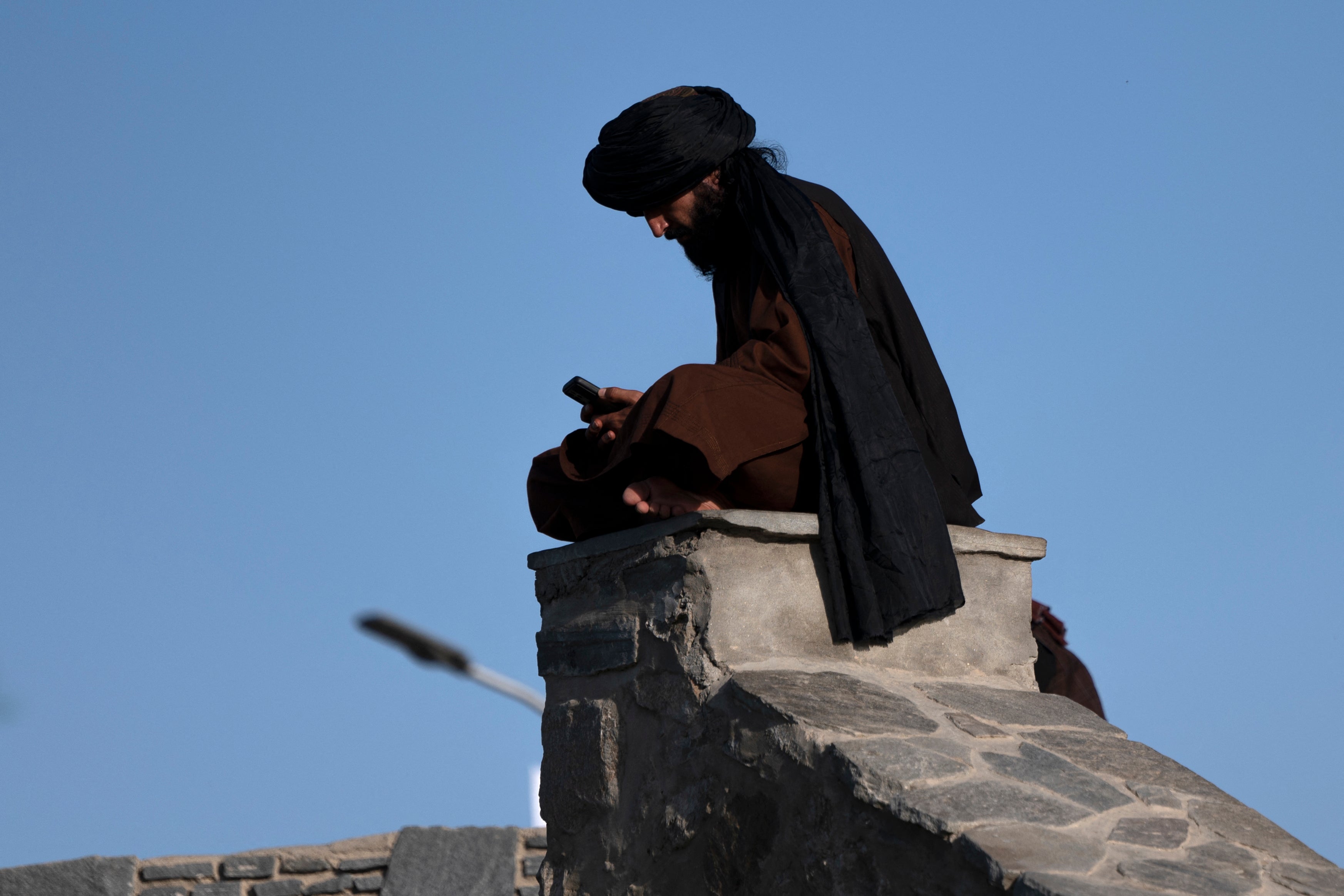 A Taliban fighter uses his phone at Wazir Akbar Khan in Kabul