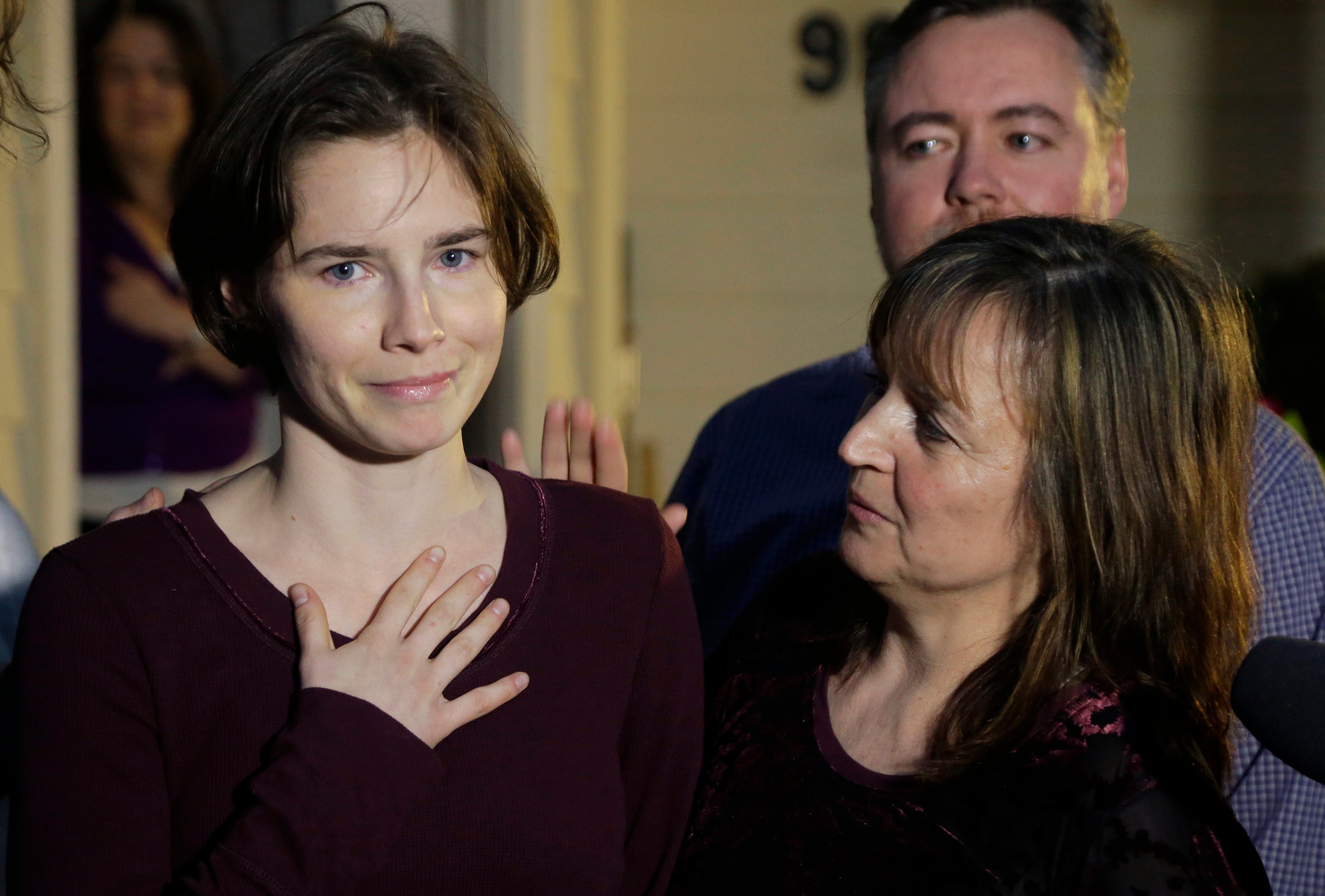 Amanda Knox, left, talks to reporters as her mother, Edda Mellas, right, looks on outside Mellas' home in Seattle