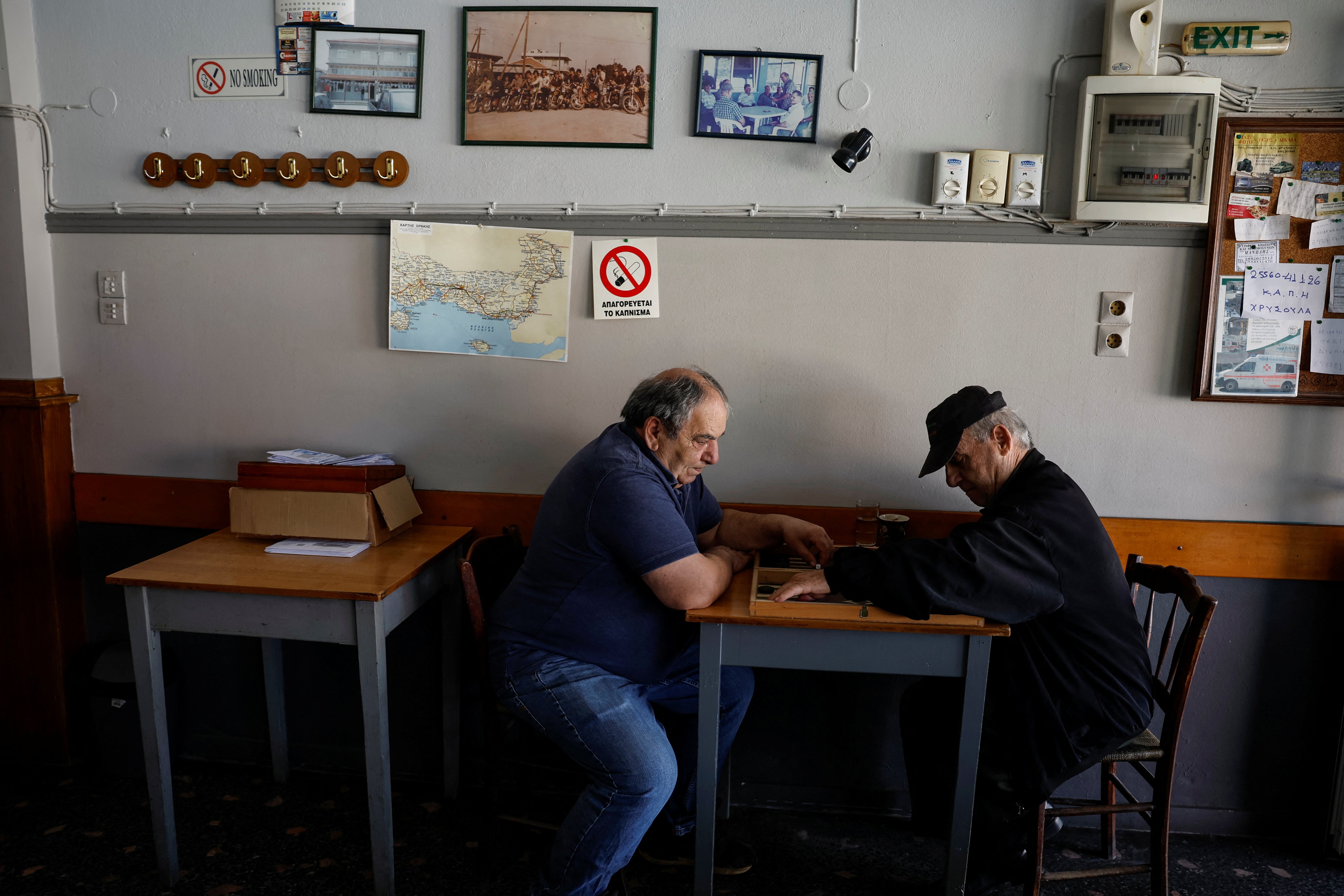 Pensioner Konstantinos Dourberidis (right), 83, plays backgammon with another man in a cafe in the village of Ormenio