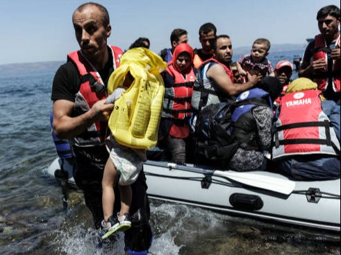 A Syrian migrant helps children get off of an inflatable boat after it arrived on the Greek island of Lesbos, after crossing the Aegean sea from Turkey