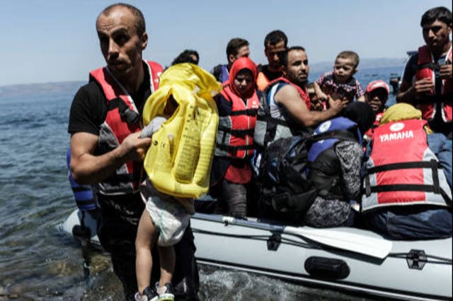 <p>A Syrian migrant helps children get off an inflatable boat after it arrived on the Greek island of Lesbos after crossing the Aegean sea from Turkey to Greece </p>