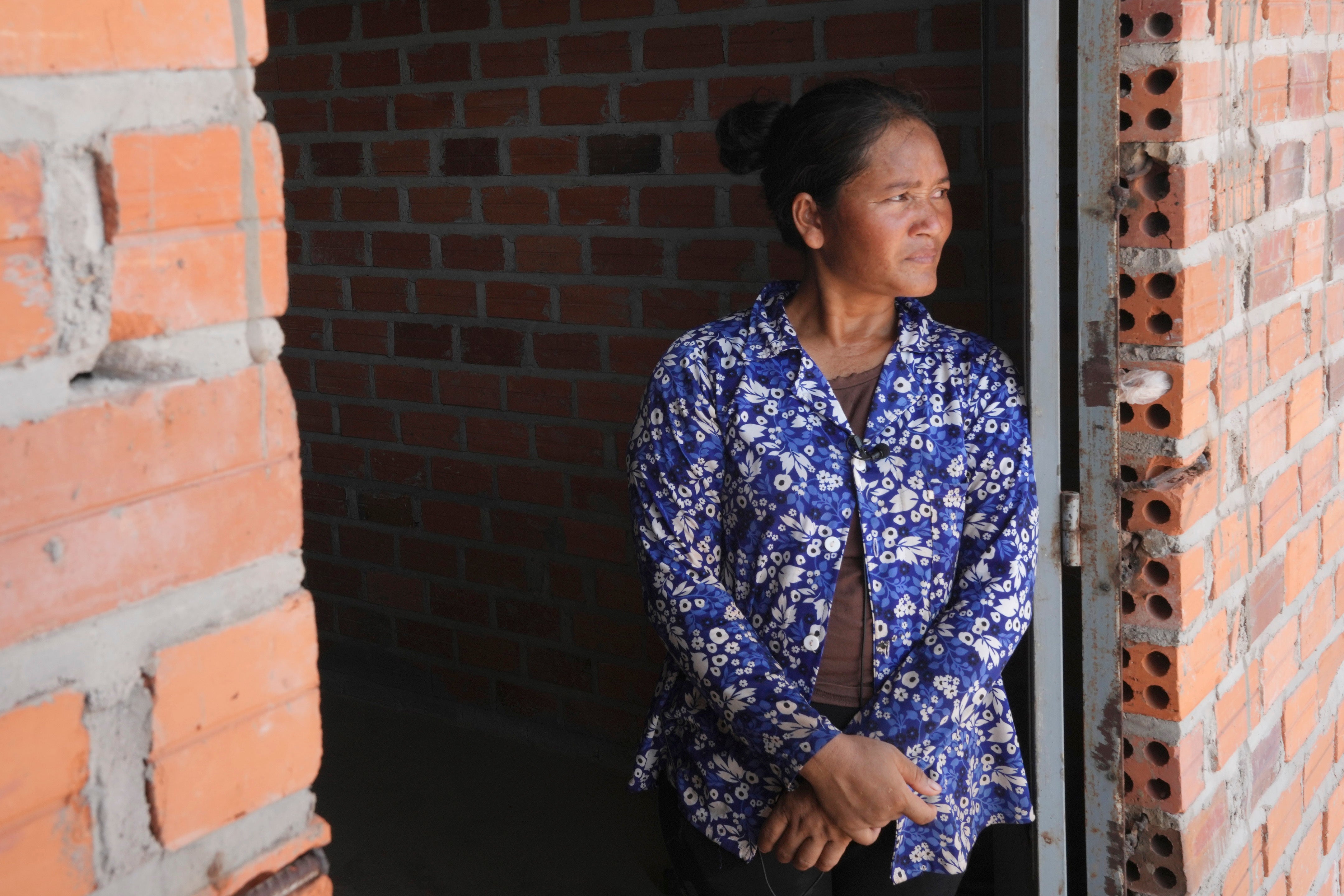 Chhem Hay, 37, stands at a main door of her house under construction at Run Ta Ek village in Siem Reap province