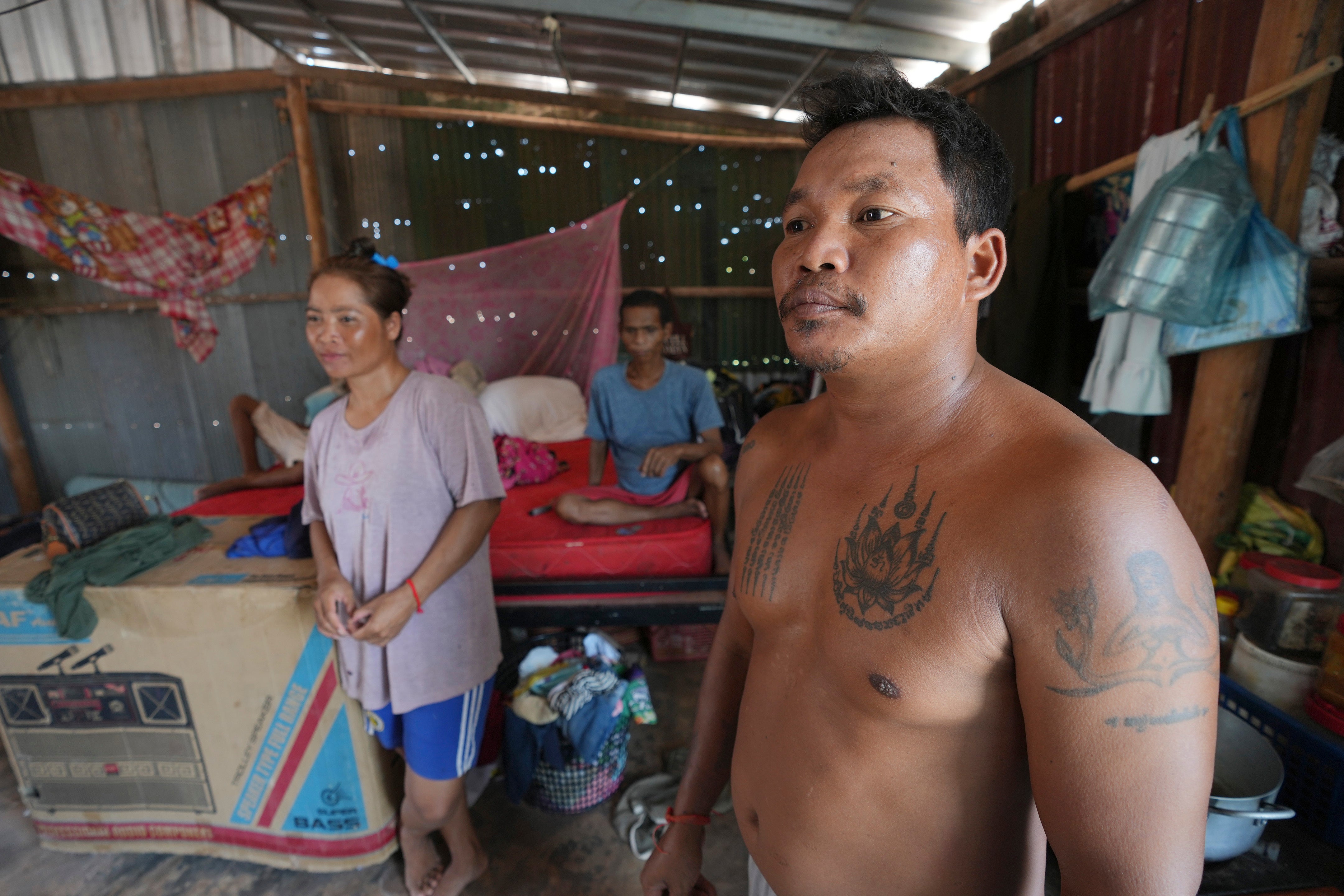 Yun Chantha, 40, right, and his wife Yem Srey Pin, 35, left, stand at their home in Run Ta Ek village in Siem Reap