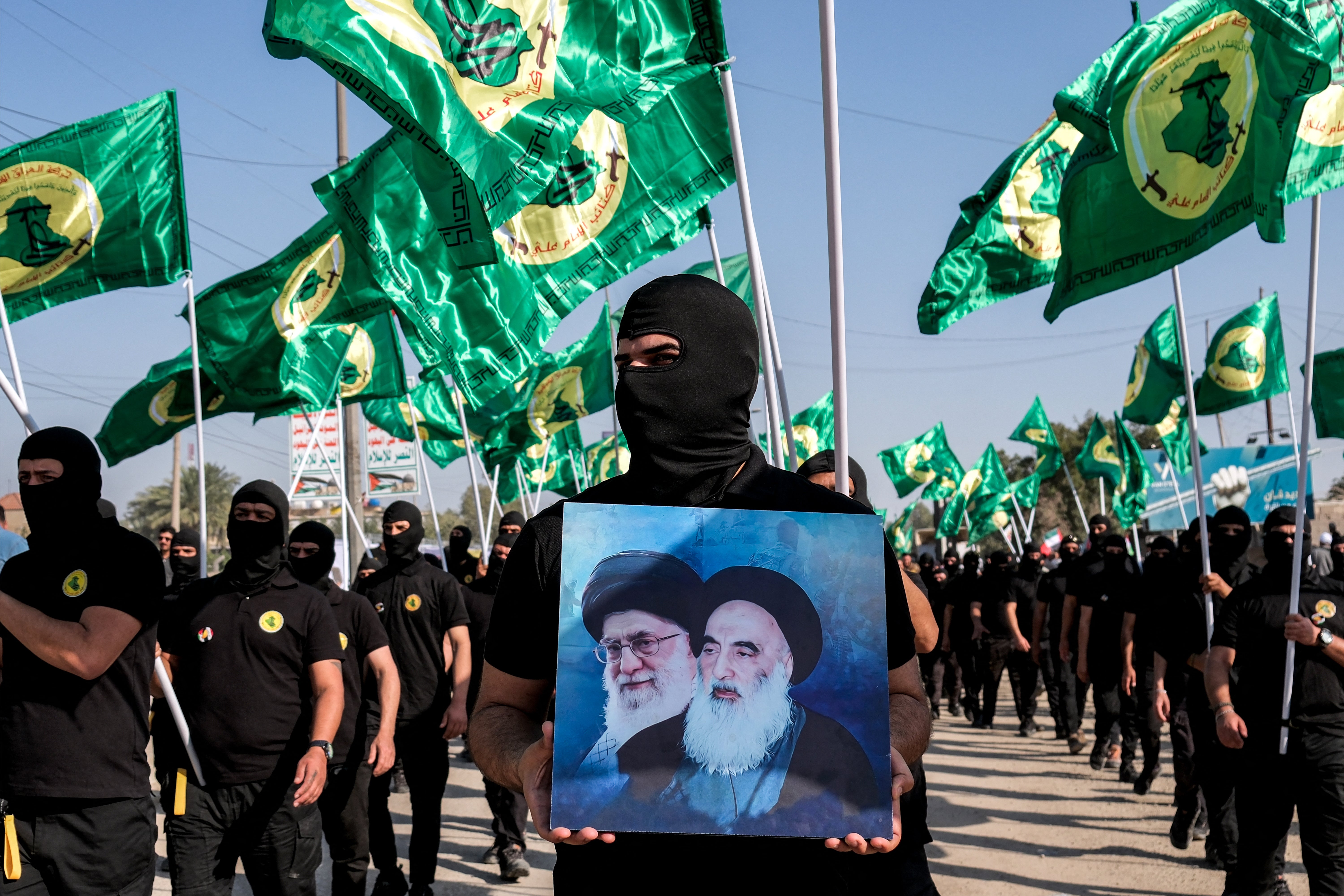 A member of an Iraqi militia holds up pictures of the former and current Iranian leaders. Ali Khamenei vowed to ‘punish’ Israel for recent attacks on Syria