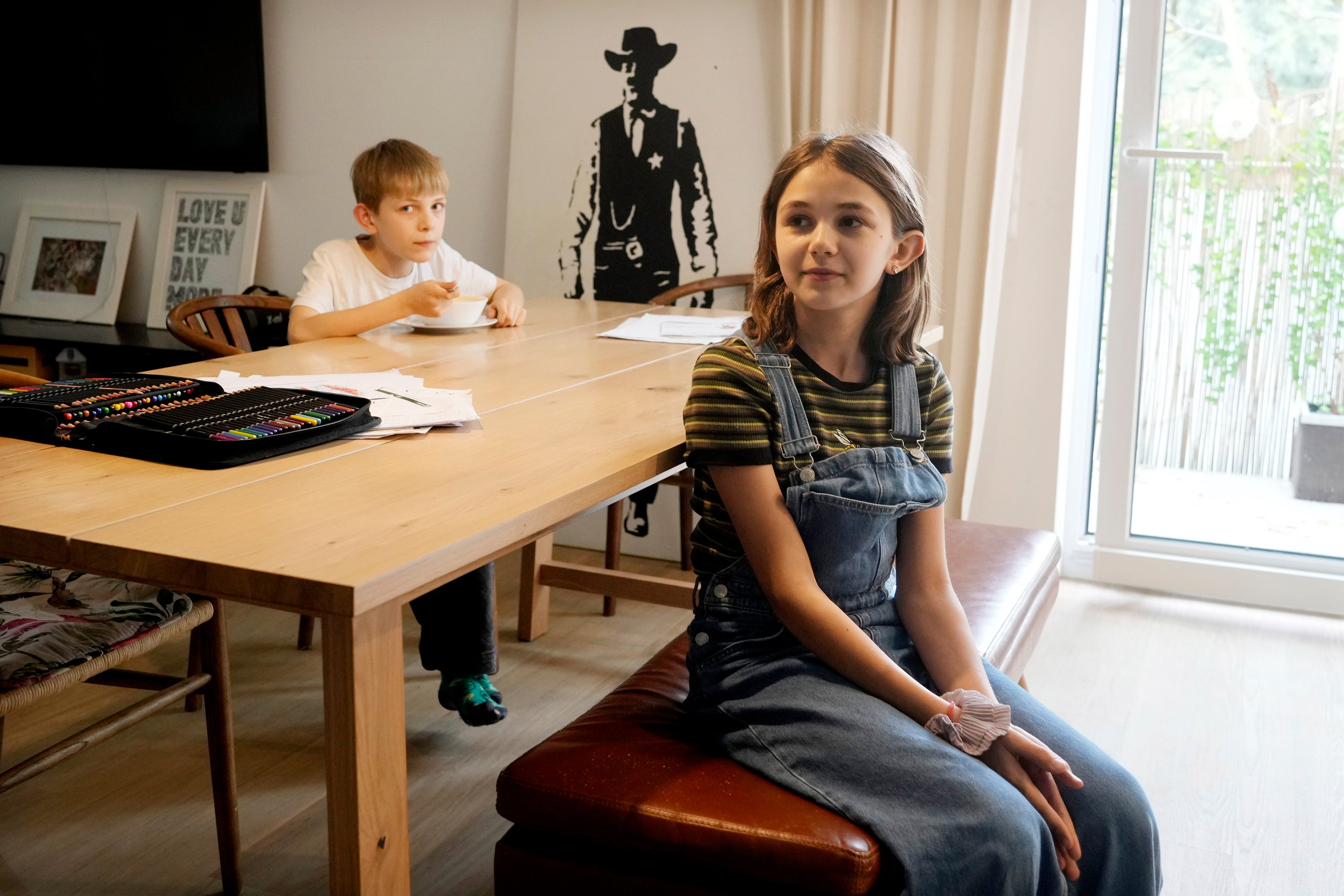 Ola Kozak, 11, right, and her younger brother Julian Kozak, 9, sit at the table where they used to do their homework