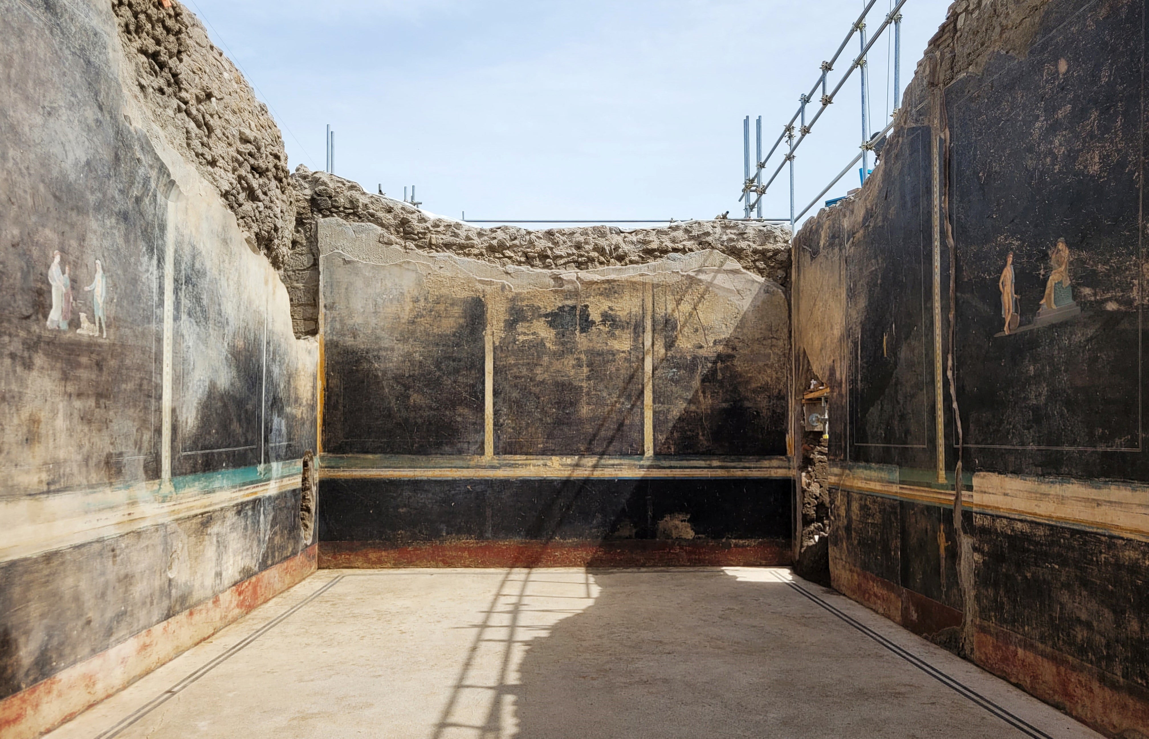 A view of a black-walled dining hall with 2,000-year old paintings inspired by the Trojan War