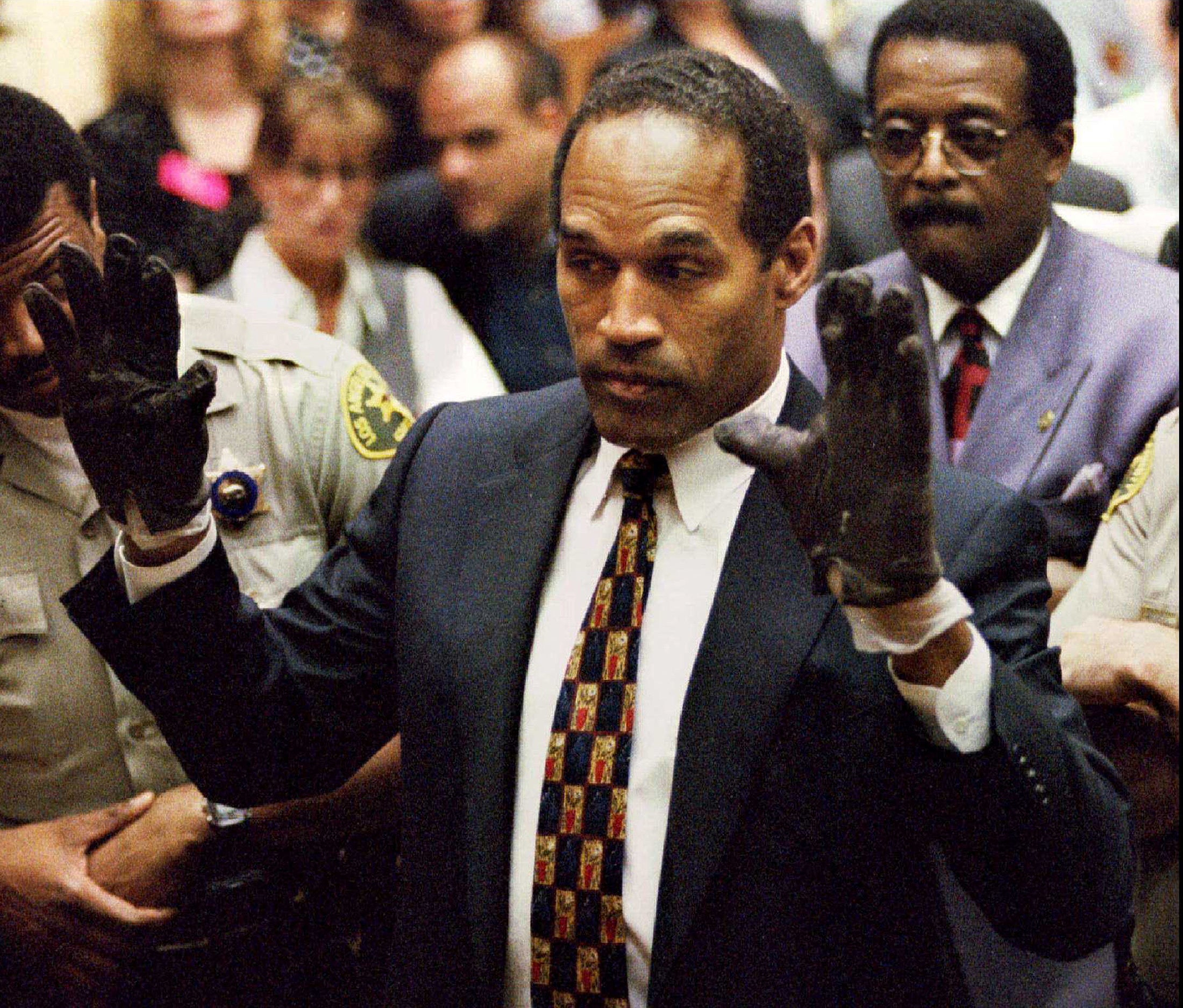 O.J. Simpson, wearing the blood stained gloves found by Los Angeles Police and entered into evidence in Simpson's murder trial, displays his hands to the jury at the request of prosecutor Christopher Darden in this file photograph from June 15, 1995