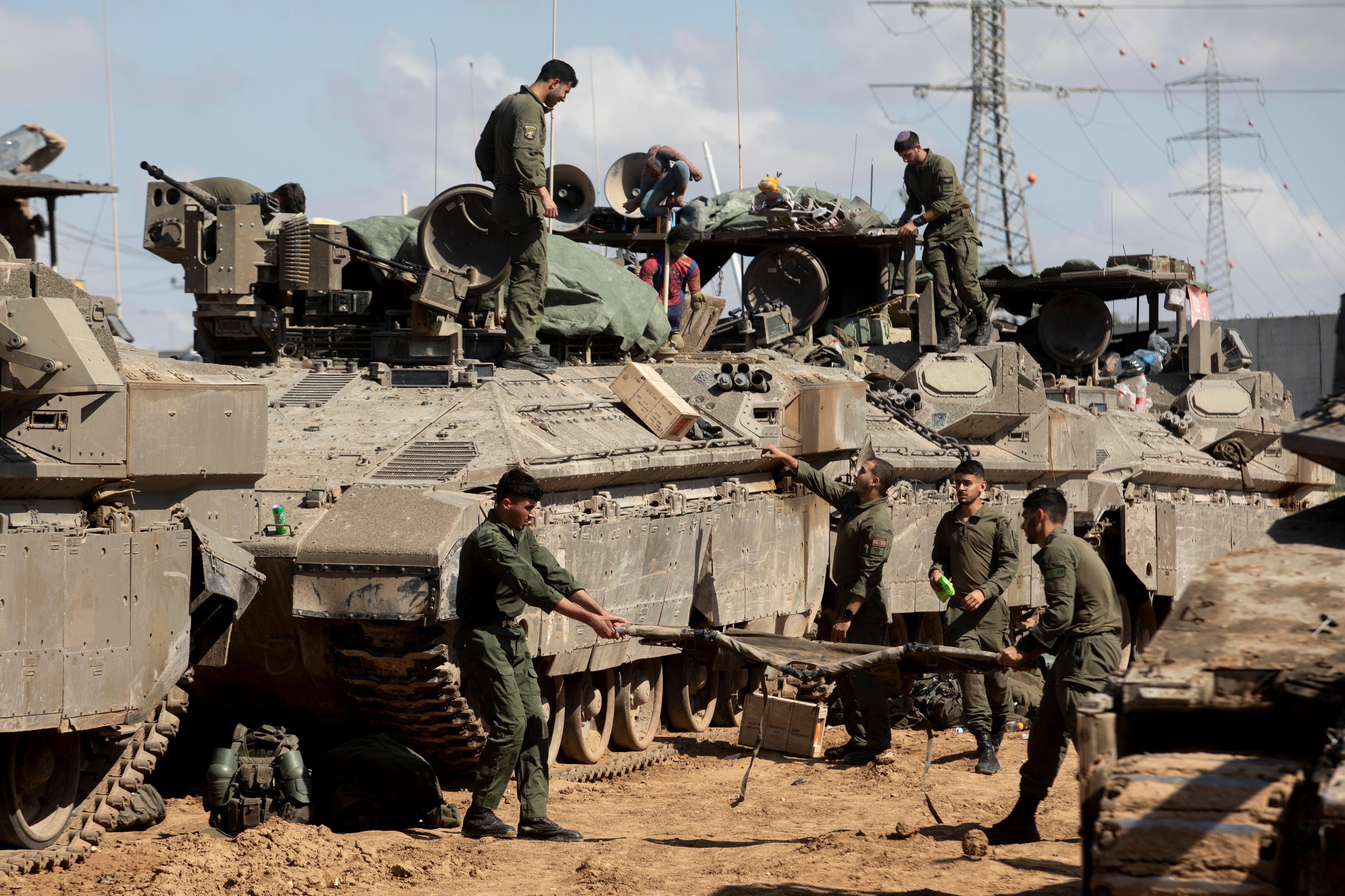 Israeli soldiers prepare their equipment and armoured personnel carriers before entering the Gaza Strip