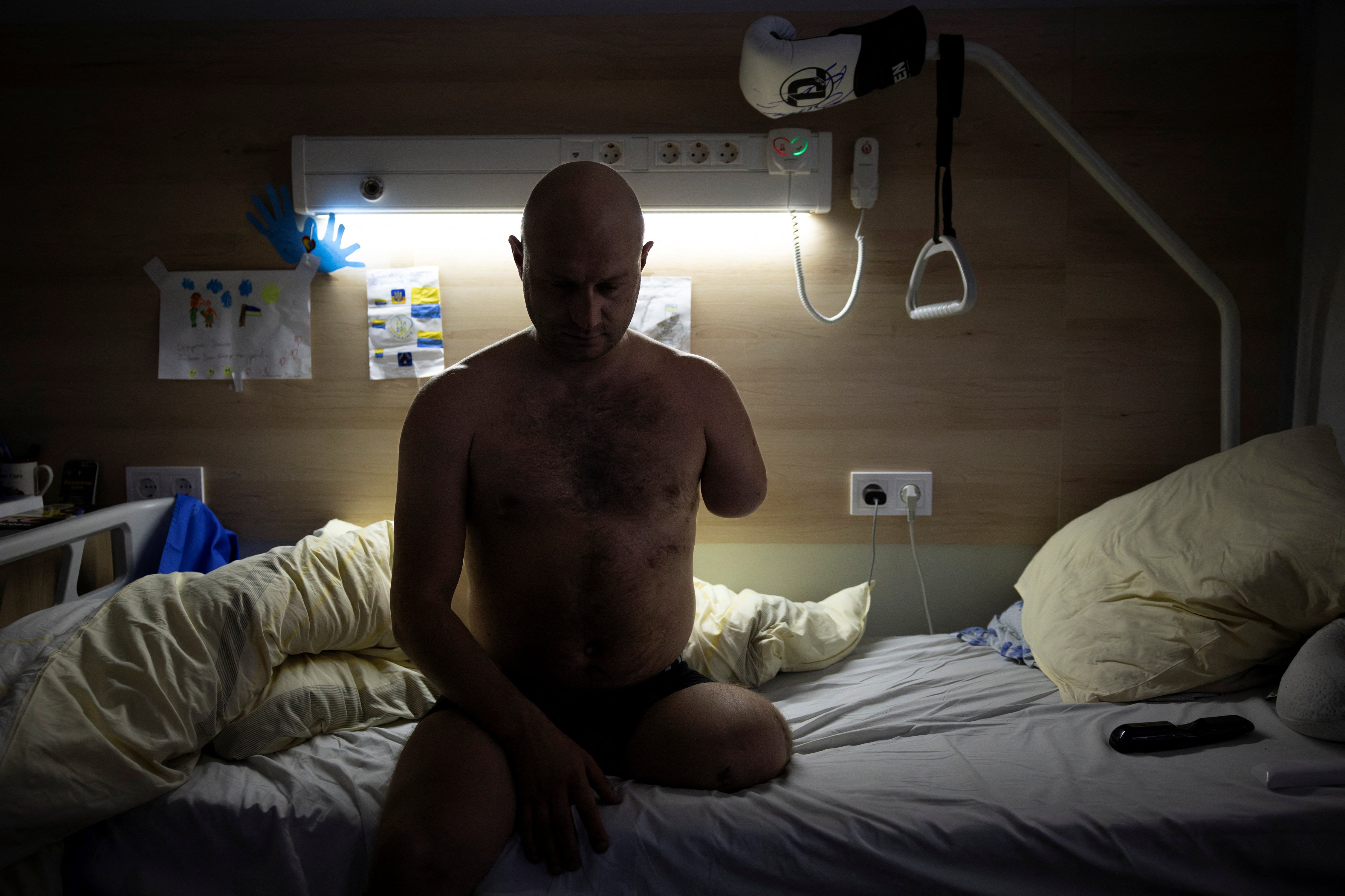 Oleksandr Revtiukh, 33, a Ukrainian serviceman who lost his left arm and most of his left leg in multiple mine blasts in 2023, sits on his bed in the Recovery Rehabilitation Center