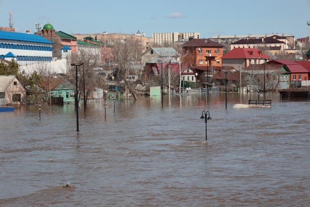 <p>Local residents stand at barriers watching a flooded area in Orenburg, Russia, on Thursday</p>