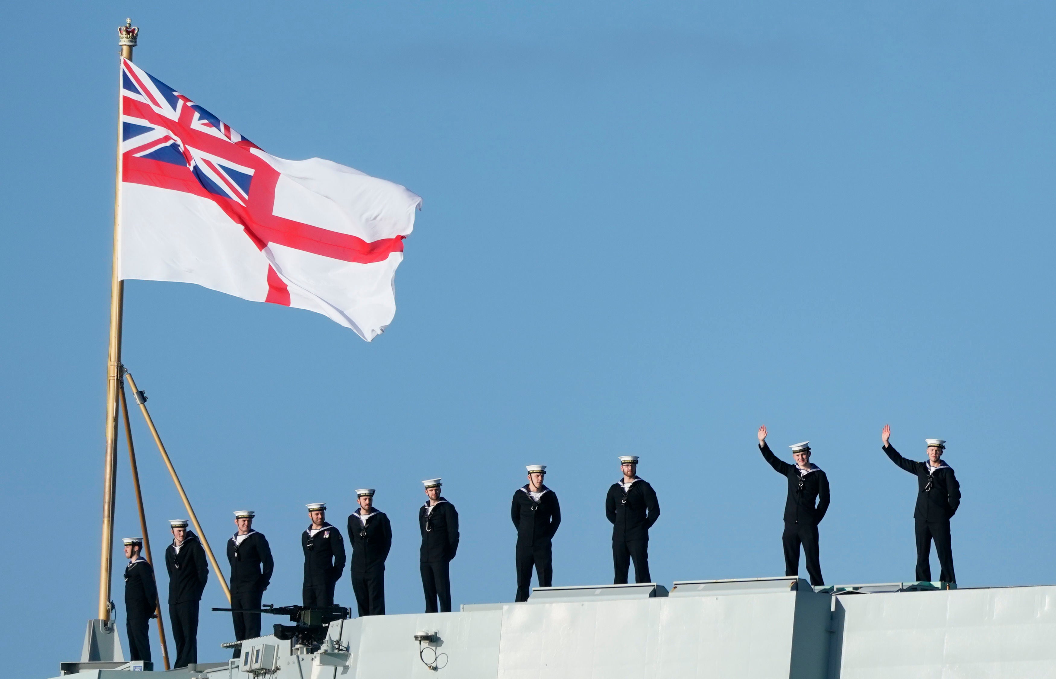 Sailors wave from the stern of the Royal Navy aircraft carrier HMS Prince of Wales as it returns to Portsmouth Naval Base following a three-month deployment to the Eastern Seaboard of the United States