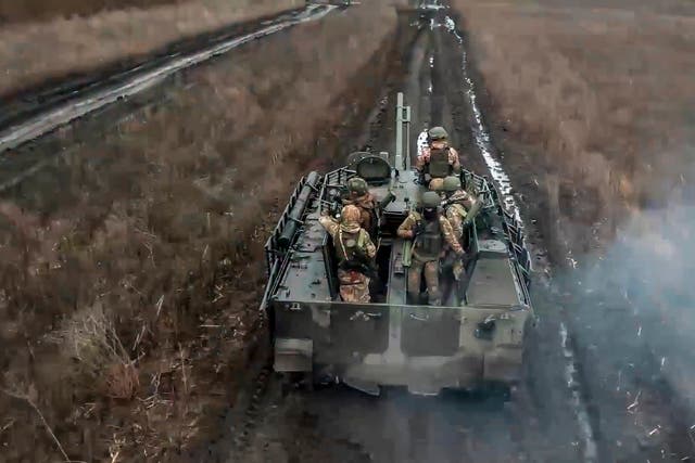 <p>Russian soldiers ride their armoured vehicle at an undisclosed location in Ukraine</p>