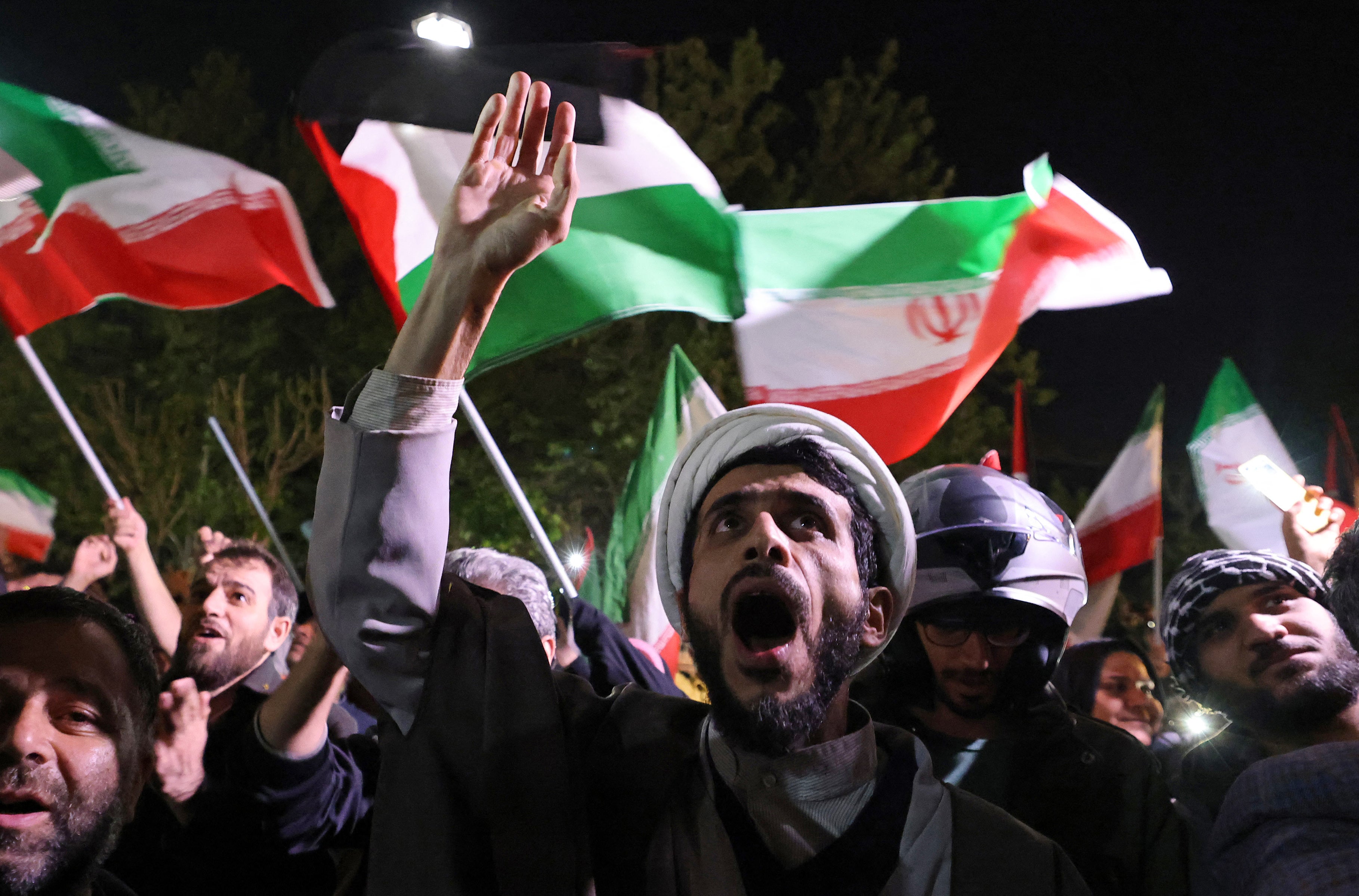 Demonstrators wave Iran’s flag as they gather in front of the British embassy in Tehran