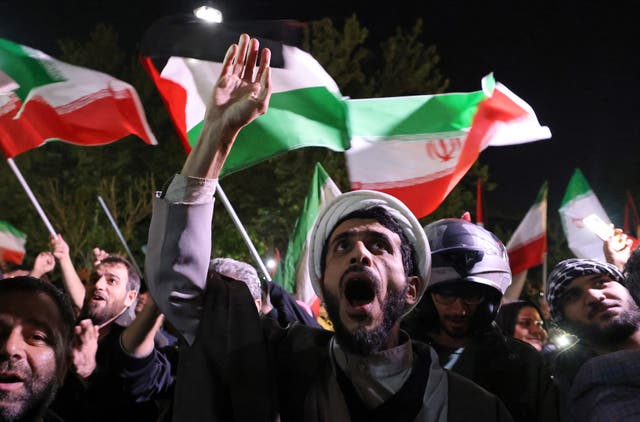 <p>Demonstrators wave Iran’s flag as they gather in front of the British embassy in Tehran</p>
