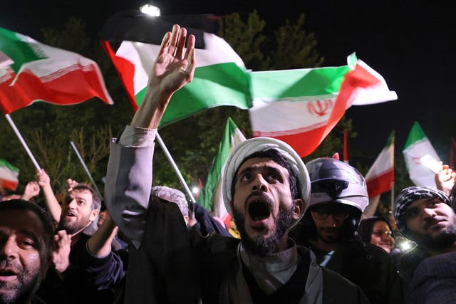 <p>Demonstrators wave Iran’s flag as they gather in front of the British embassy in Tehran</p>