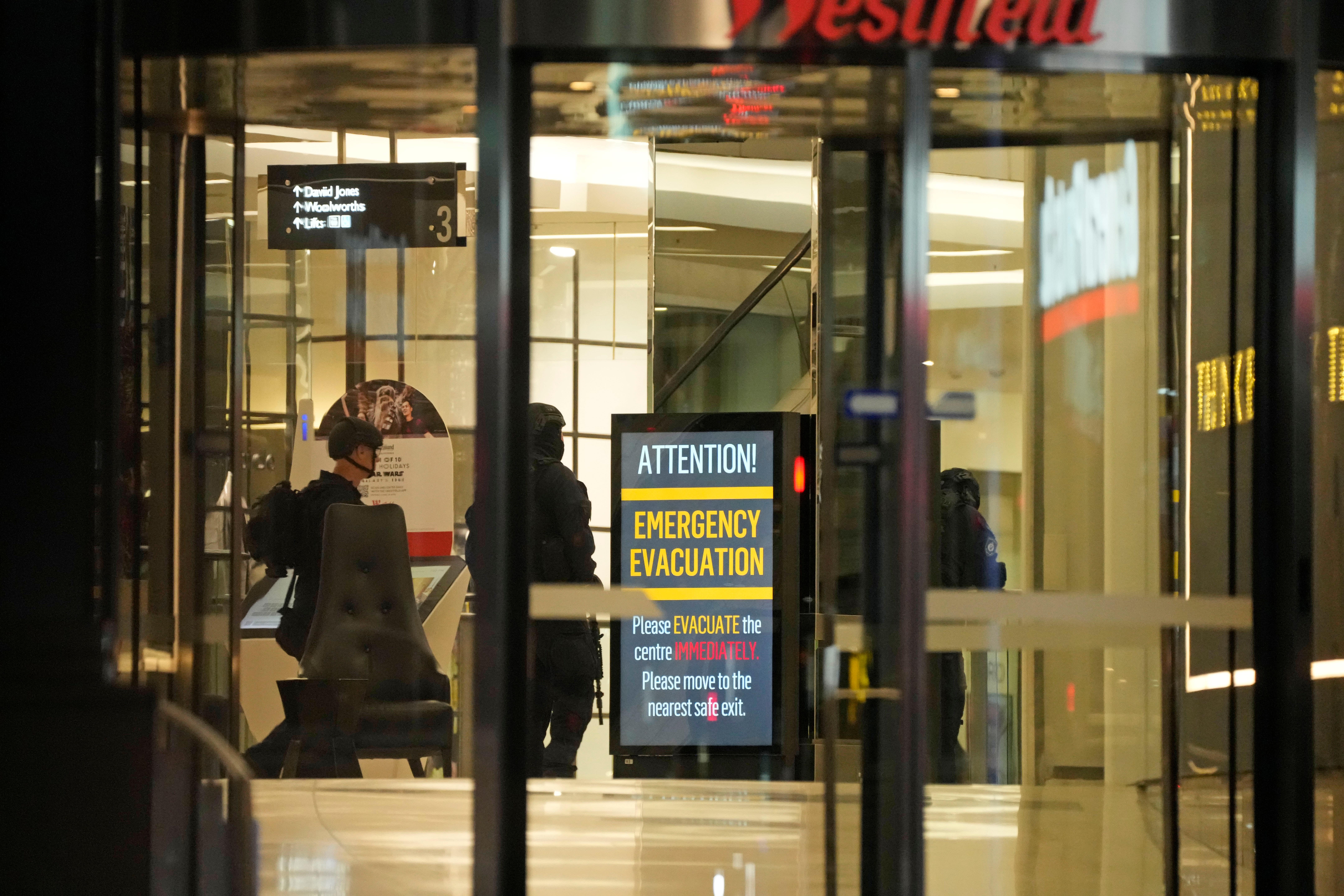 Police officers walk past a sign at Westfield Shopping Centre on Saturday
