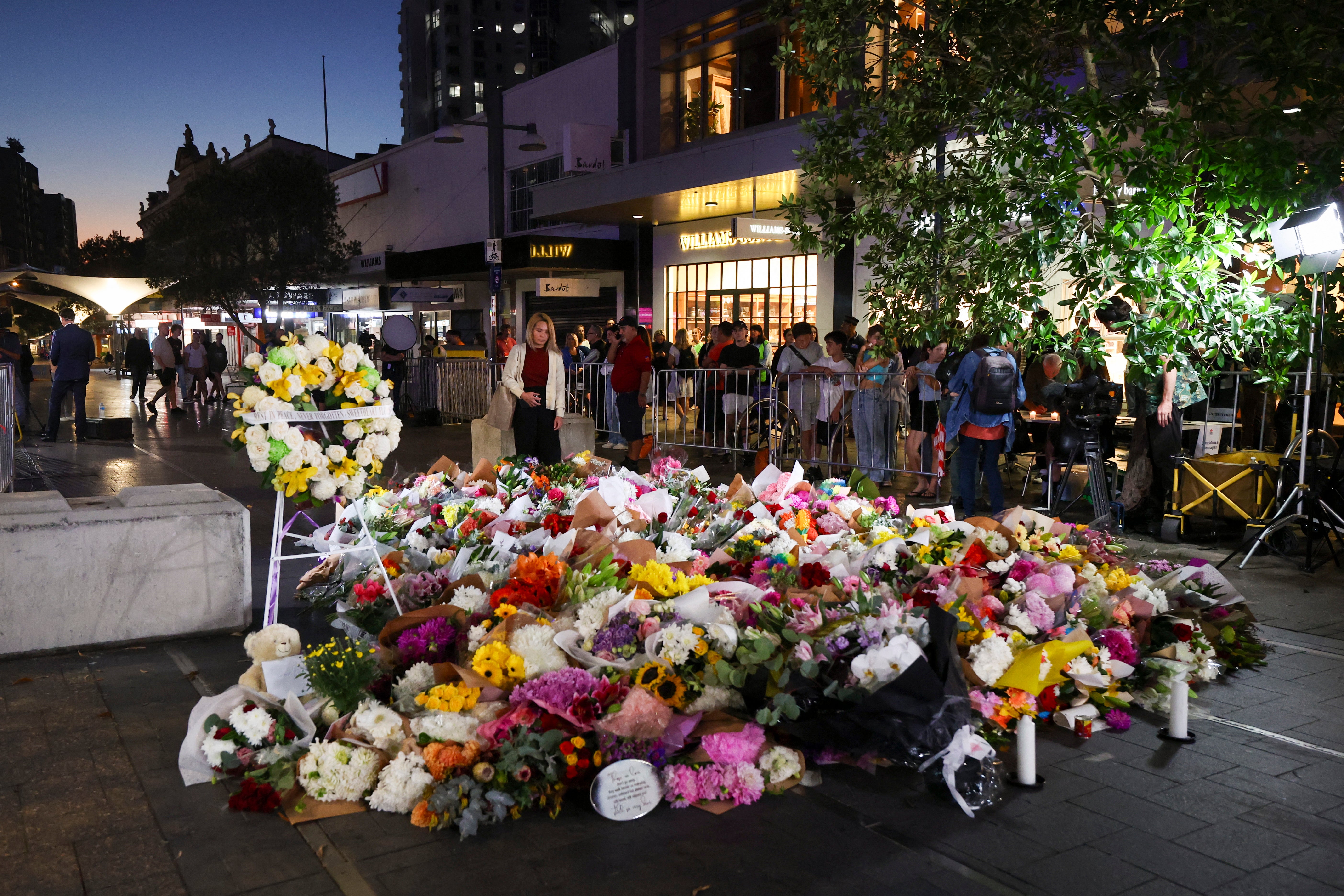 <p>A woman leaves flowers outside the Westfield shopping mall in Sydney on April 14, 2024</p>