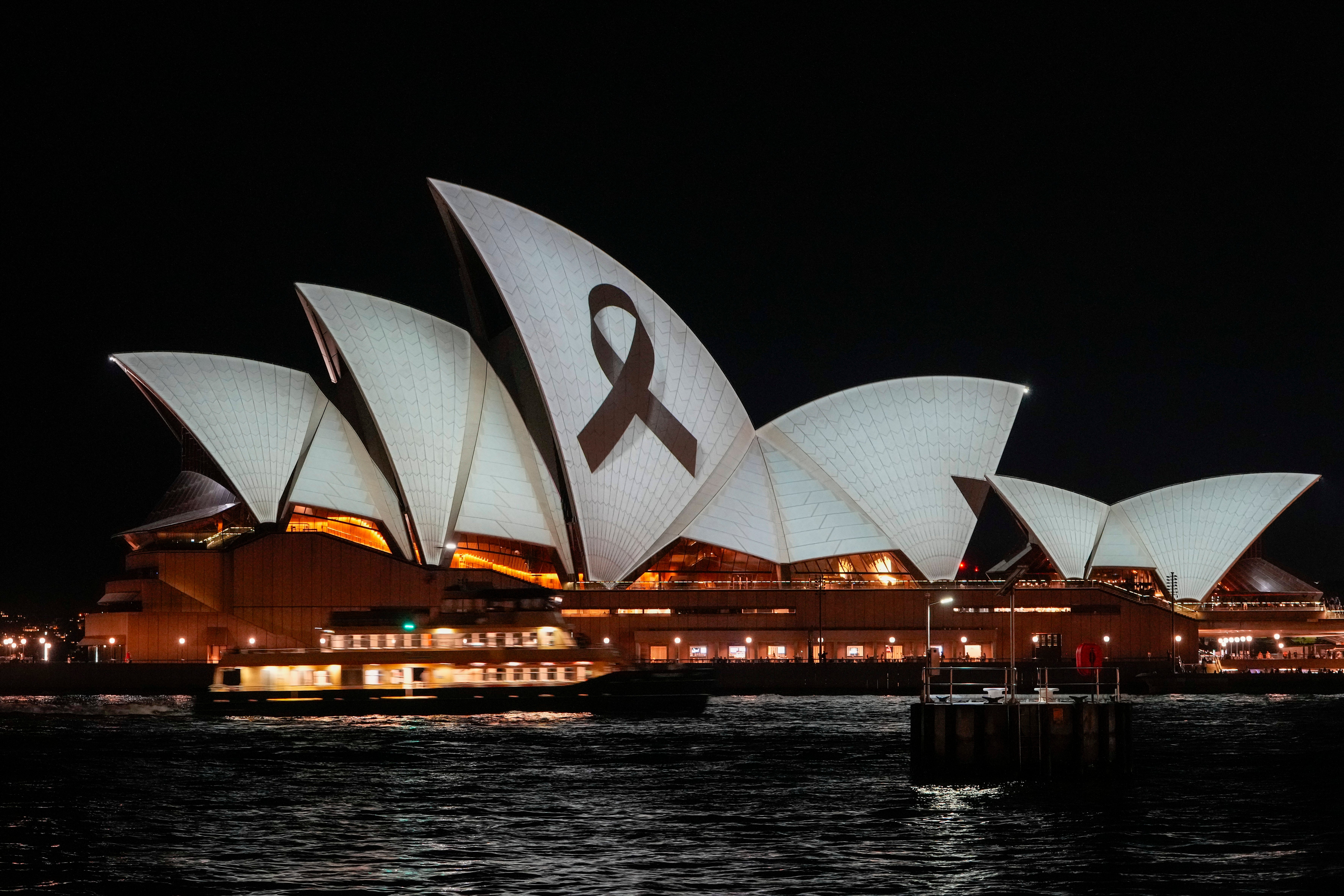 The Sydney Opera House is illuminated with a black ribbon as part of the national day of mourning