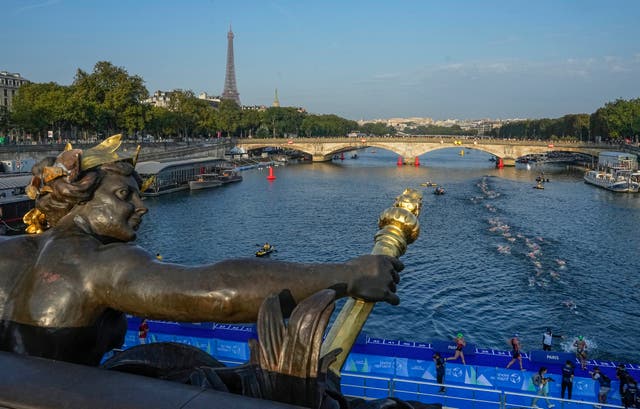 <p>Athletes dive and swim in the Seine river from the Alexander III bridge on the first leg of the women’s triathlon test </p>
