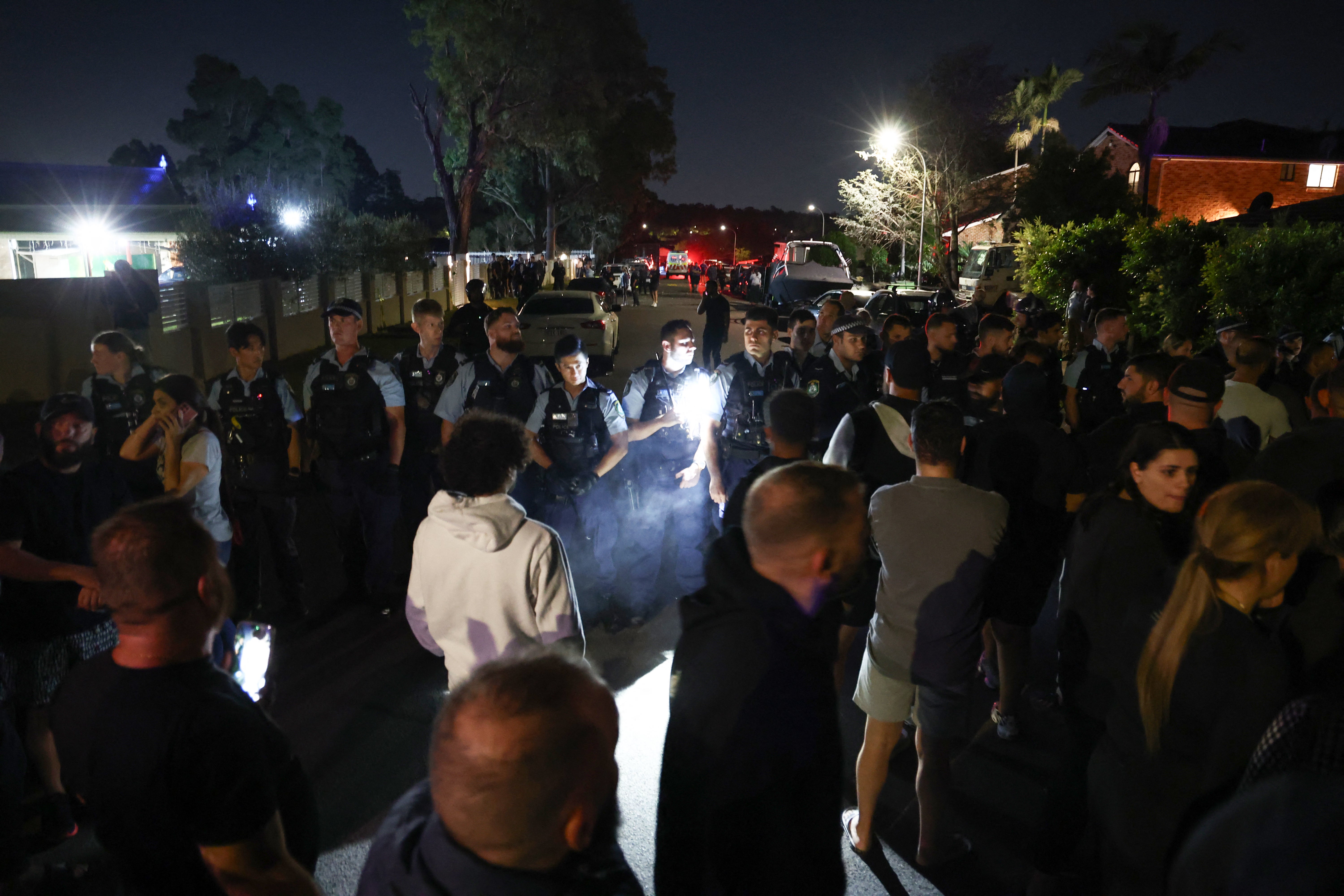 Locals gather with police guarding the perimeter of the Christ the Good Shepherd Church in Sydney