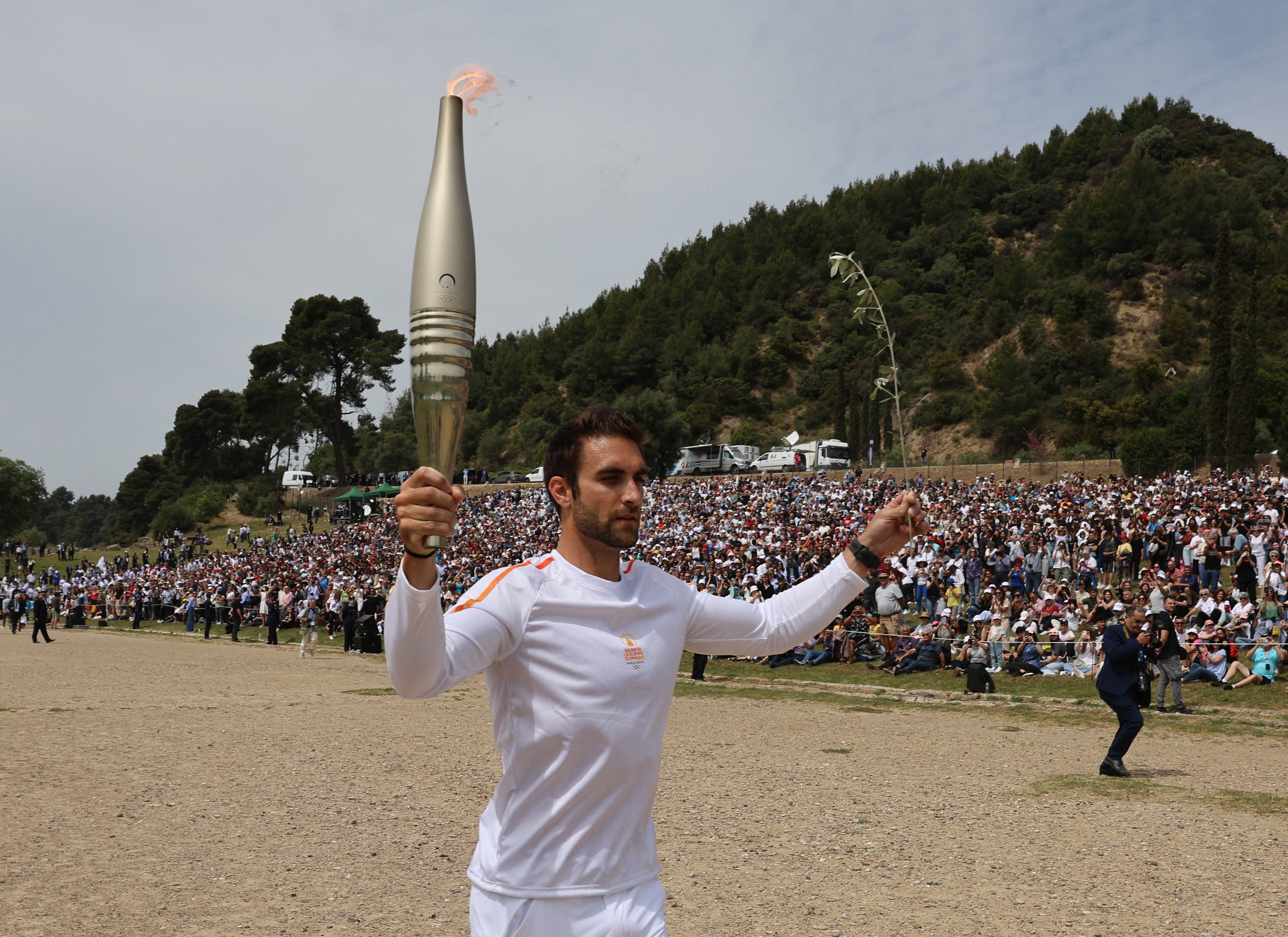 Greek rower Stefanos Ntouskos carries the Olympic Flame during the start of the torch relay for the Paris 2024 games