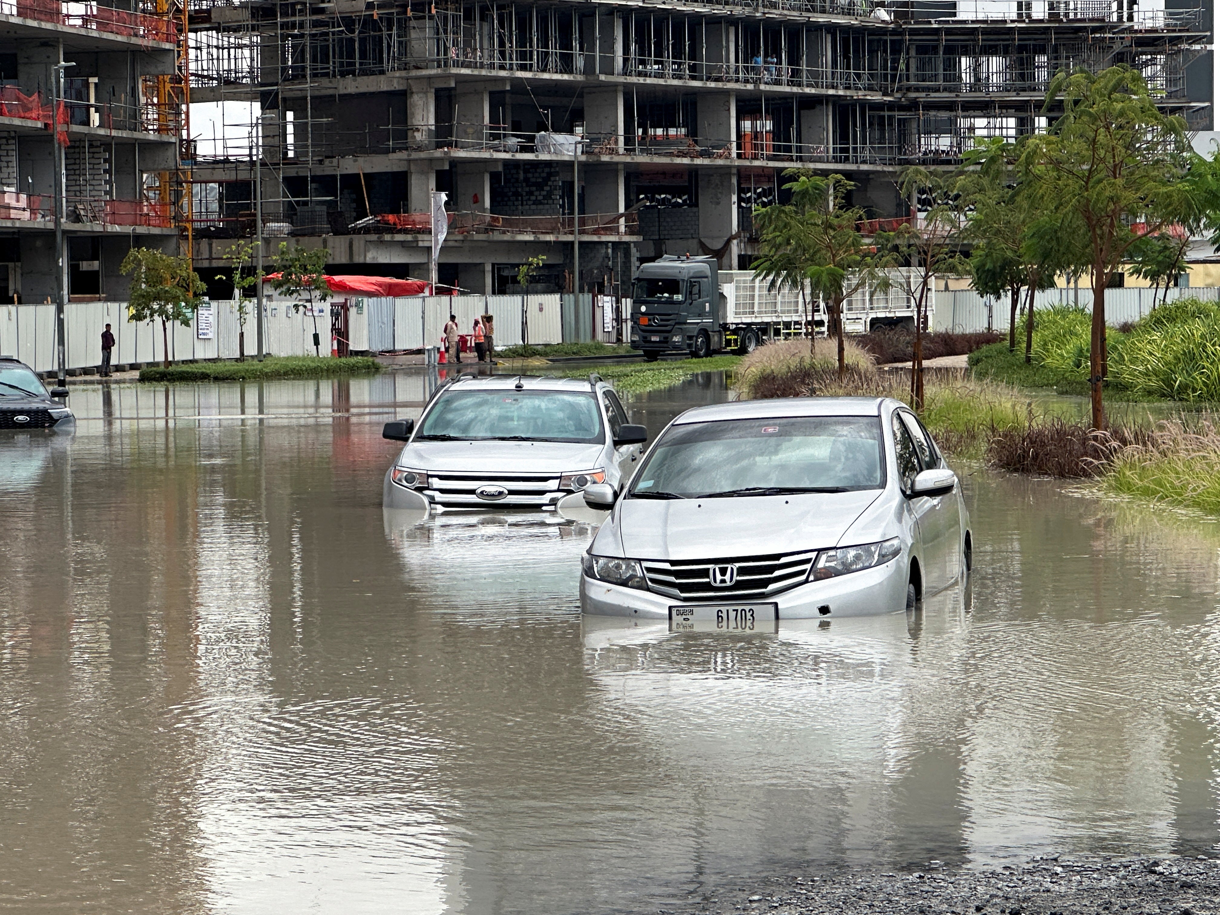 Cars drive through a flooded street