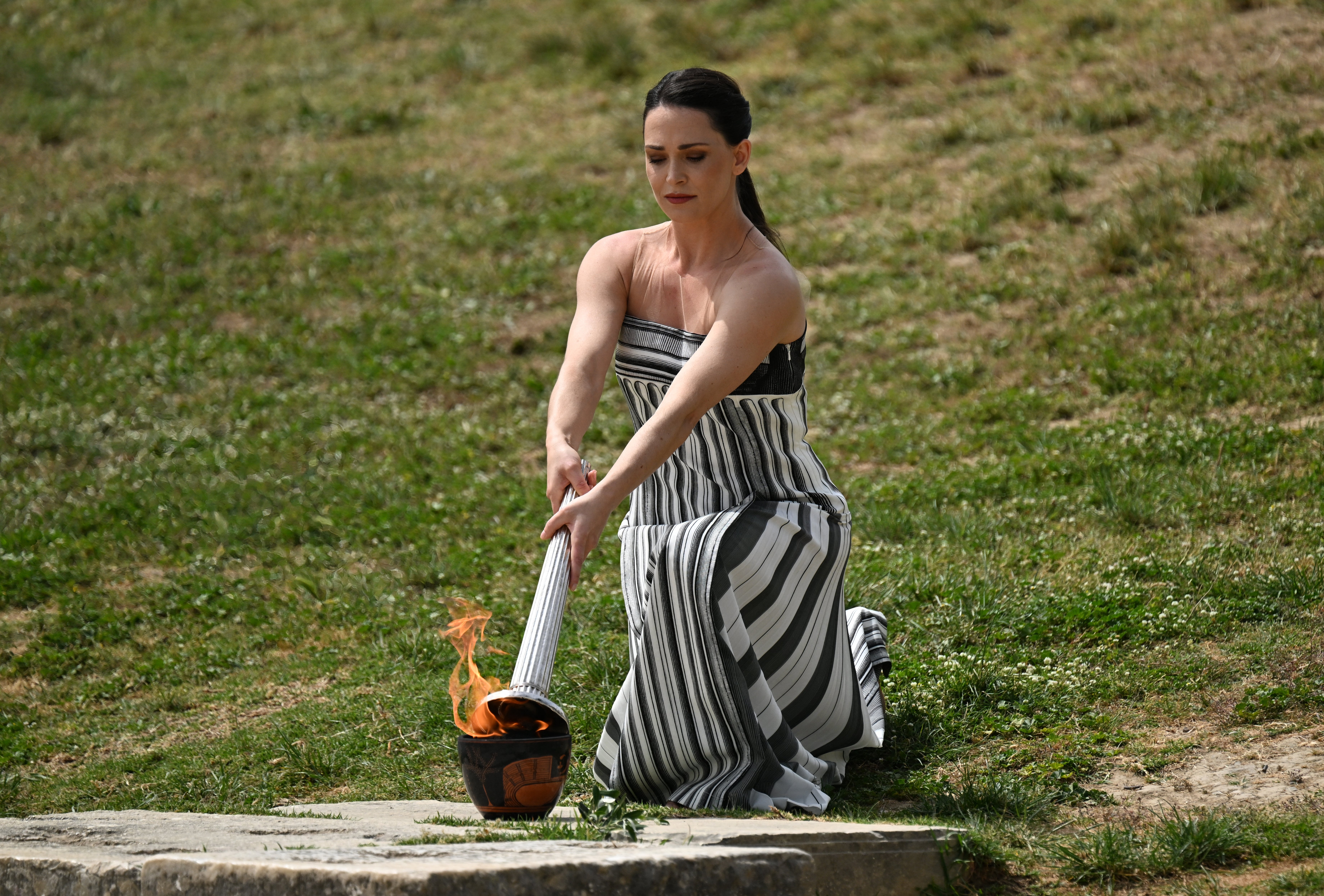 Greek actress Mary Mina, playing the role of the High Priestess, lights the Olympic torch during the flame lighting ceremony