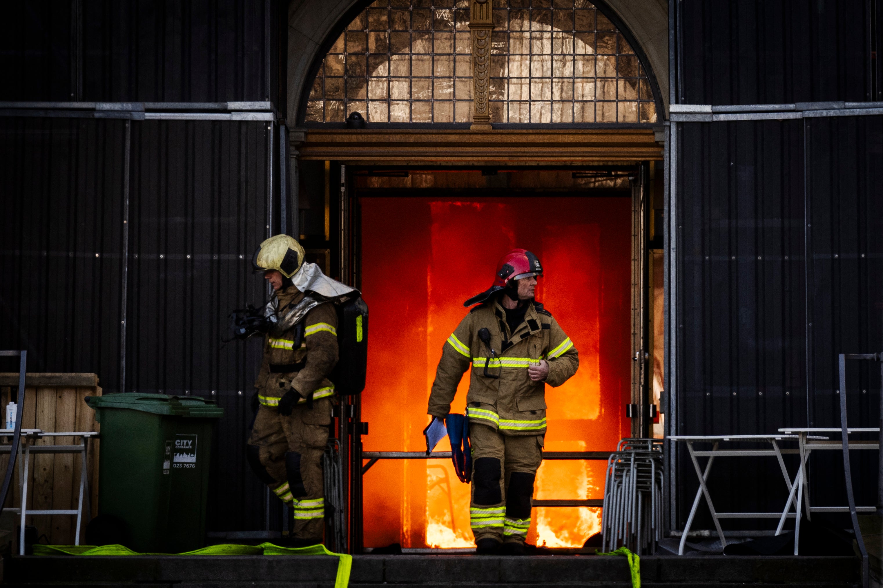 Firefighters exit the burning innards of the building