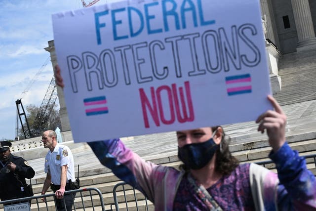 <p>An activist holds a sign calling for federal protections of transgender rights, in front of the US Supreme Court in Washington, DC, on 1 April 2023</p>