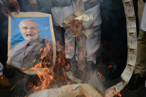 Supporters of the opposition Congress burn old 500 rupee notes and a poster bearing the image of prime minister Narendra Modi during a protest against demonetisation