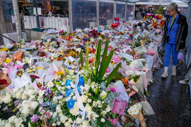<p>A woman walks past flowers at a tribute for the victims of Saturday's knife attack near a crime scene at Bondi Junction in Sydney</p>