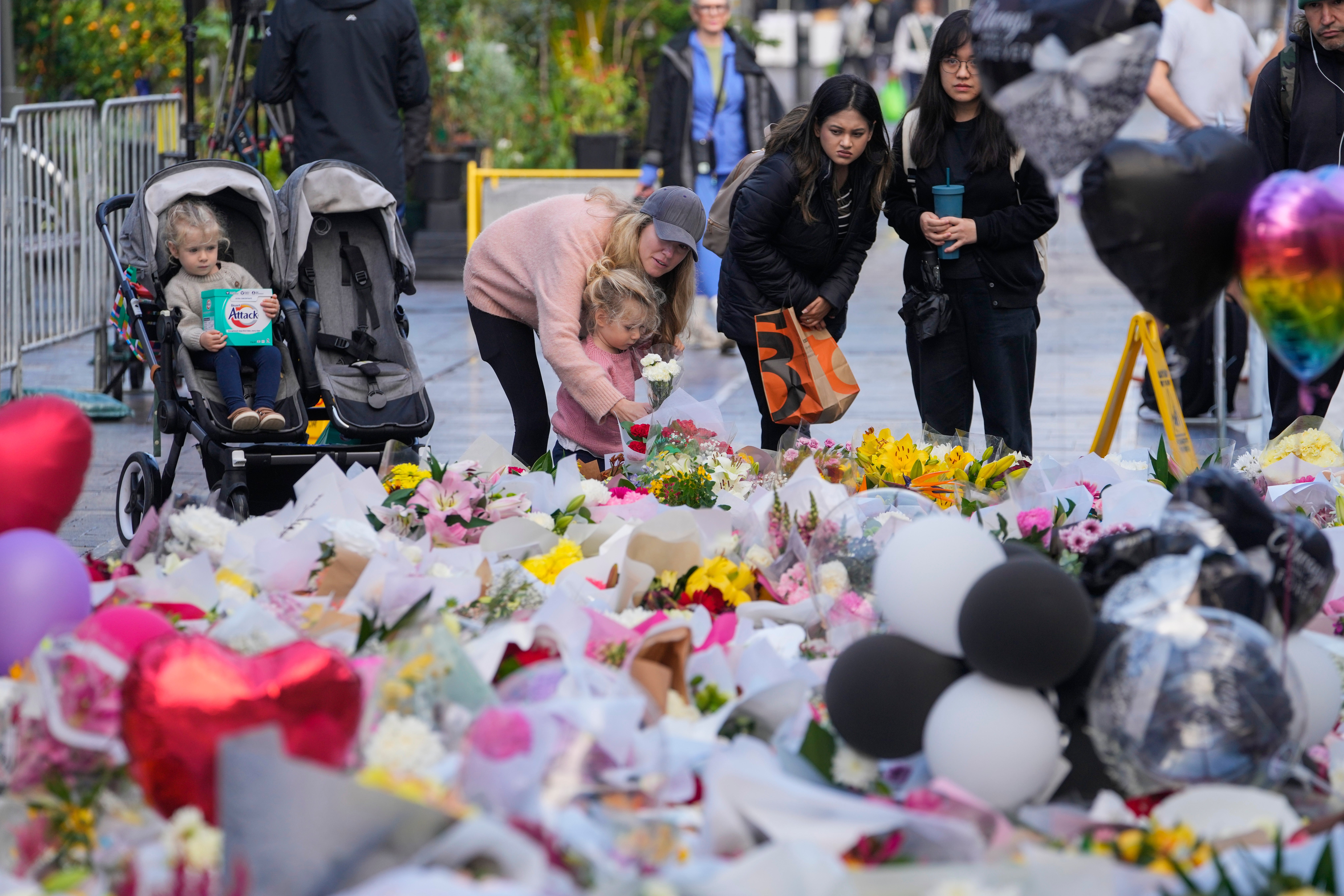 People lay flowers at a tribute for the victims in Saturday’s knife attack