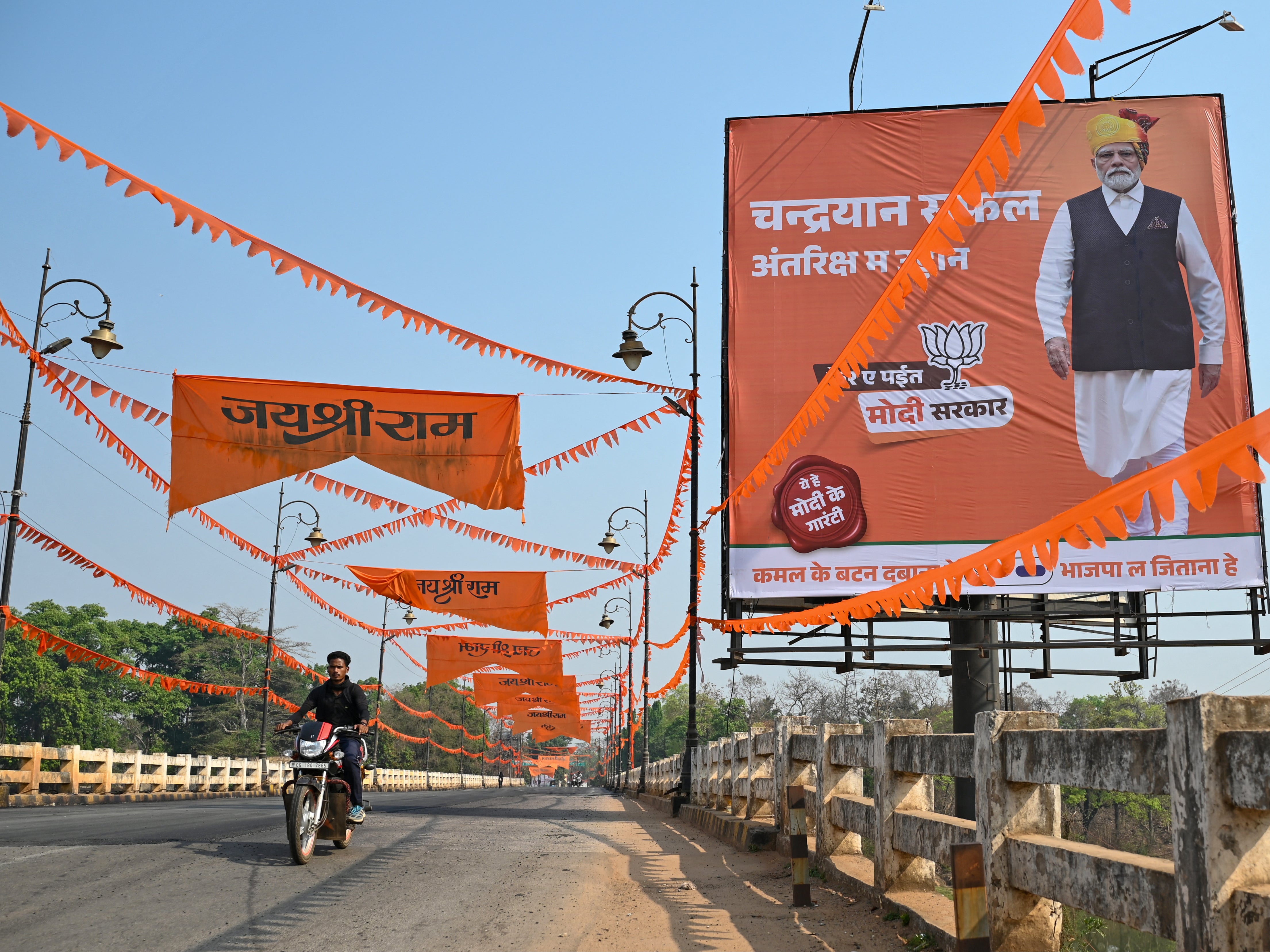 A motorcyclist drives past a poster of India’s prime minister Narendra Modi in Dantewada, Chhattisgarh, ahead of India’s national election