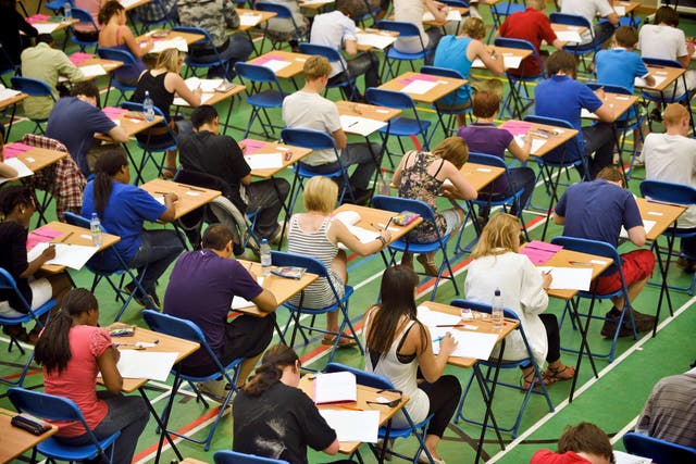 <p>A-level students sit an A-level maths exam inside a sports hall</p>