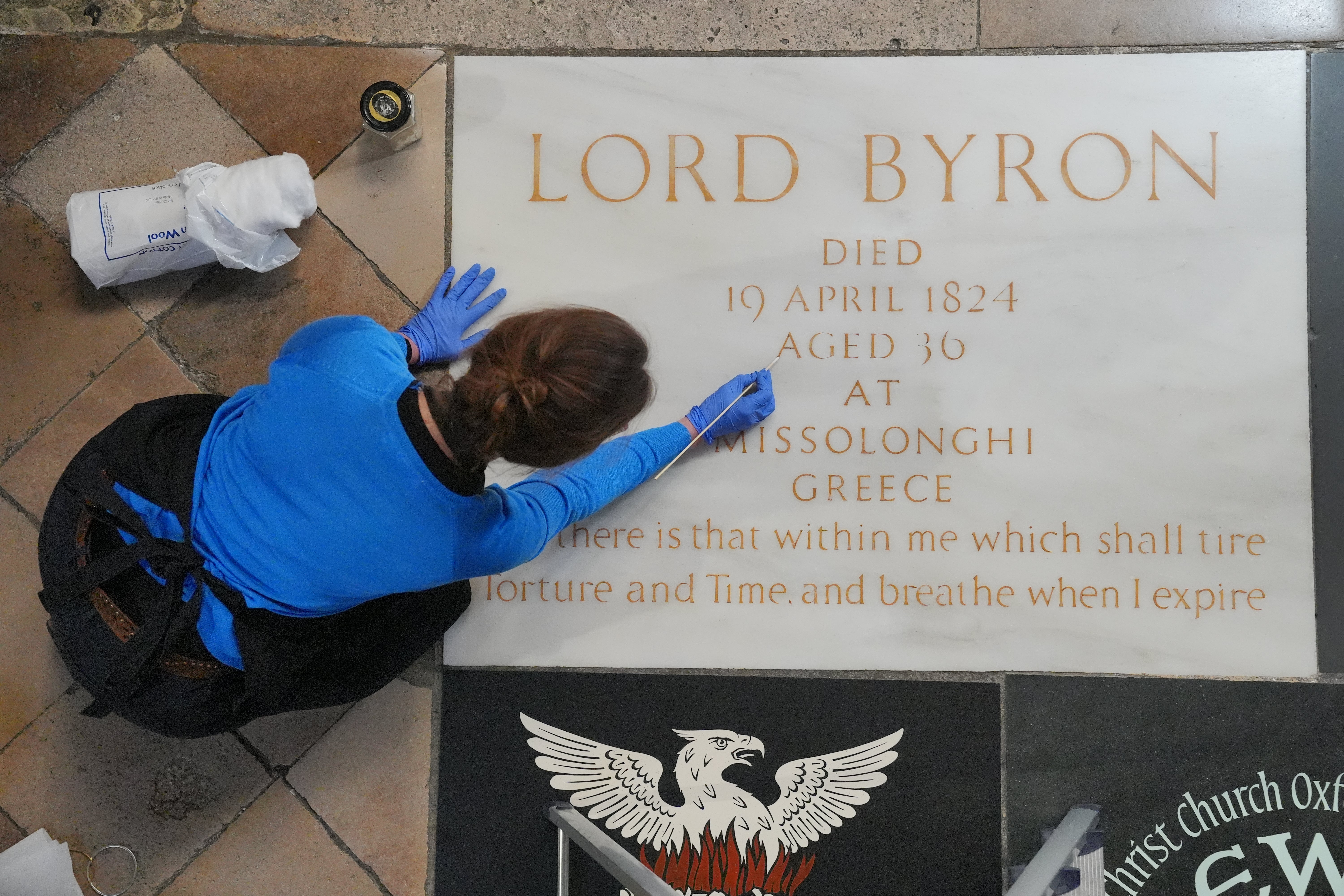 A conservator cleans Lord Byron's memorial stone in Poets' Corner at Westminster Abbey in London, ahead of the 200th anniversary of his death