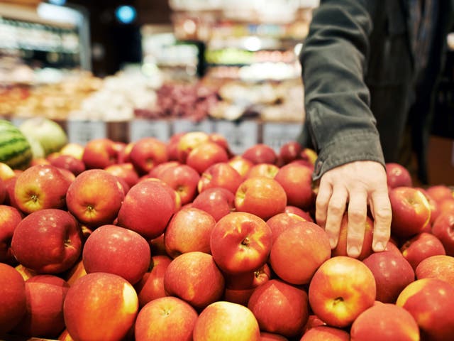 <p>A person shopping for apples in a grocery store.</p>