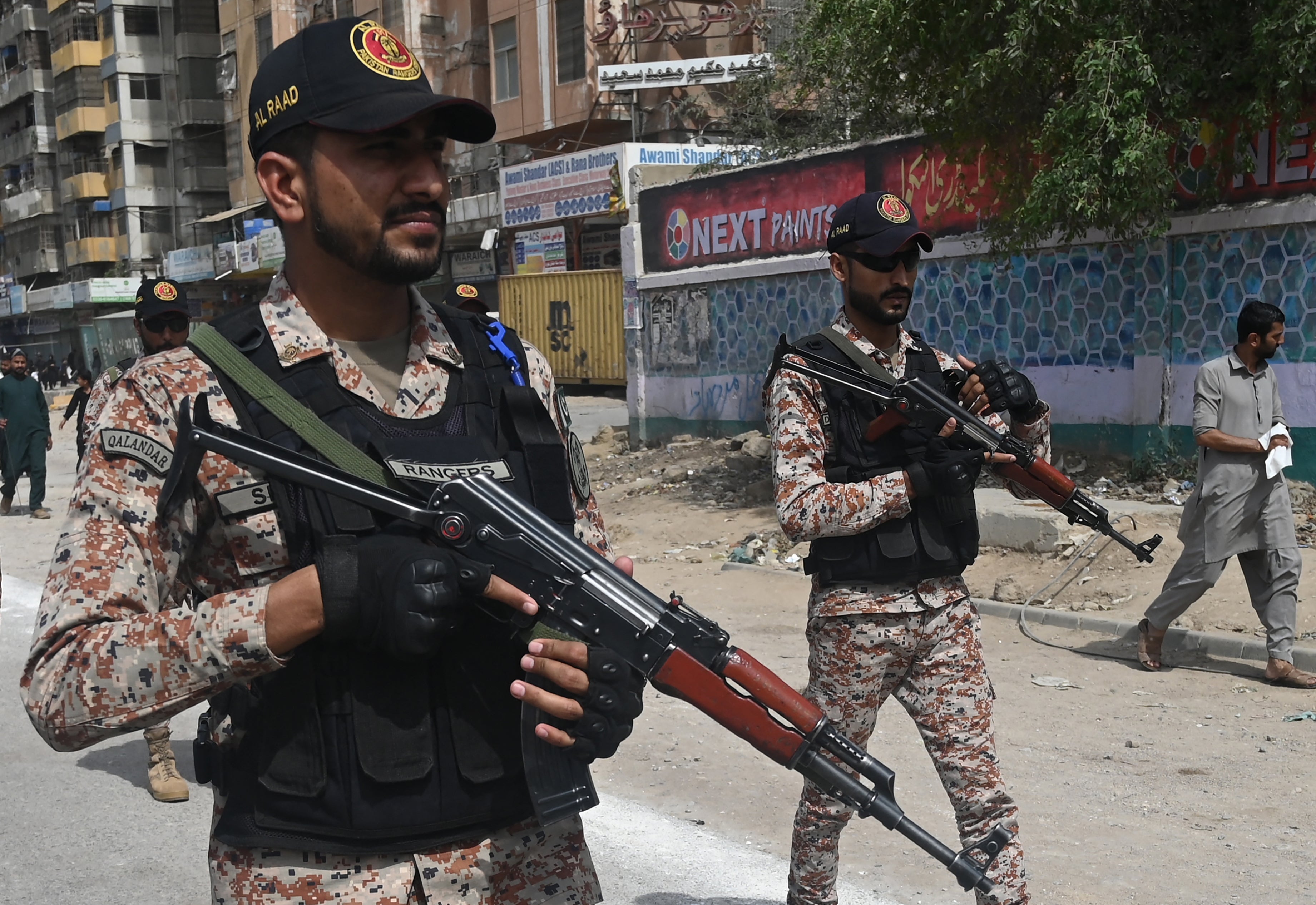 Security personnel patrol along a street in Karachi