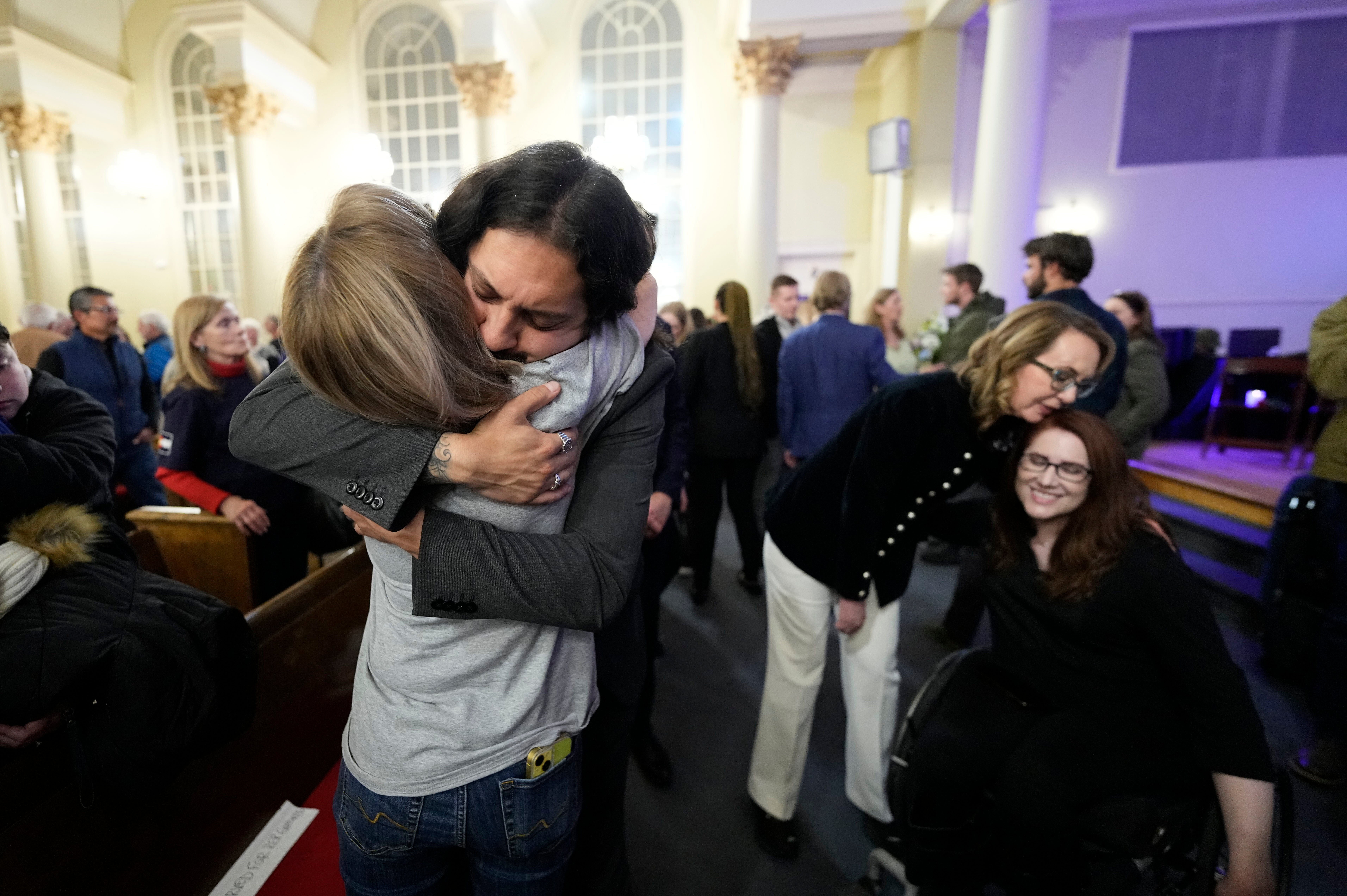 Tim Hernandez hugs Kallie Leyba as former Arizona Rep. Gabby Giffords, second from right, hugs Anne Marie Hochhalter, right during a vigil remembering the 25th anniversary of the Columbine High School mass