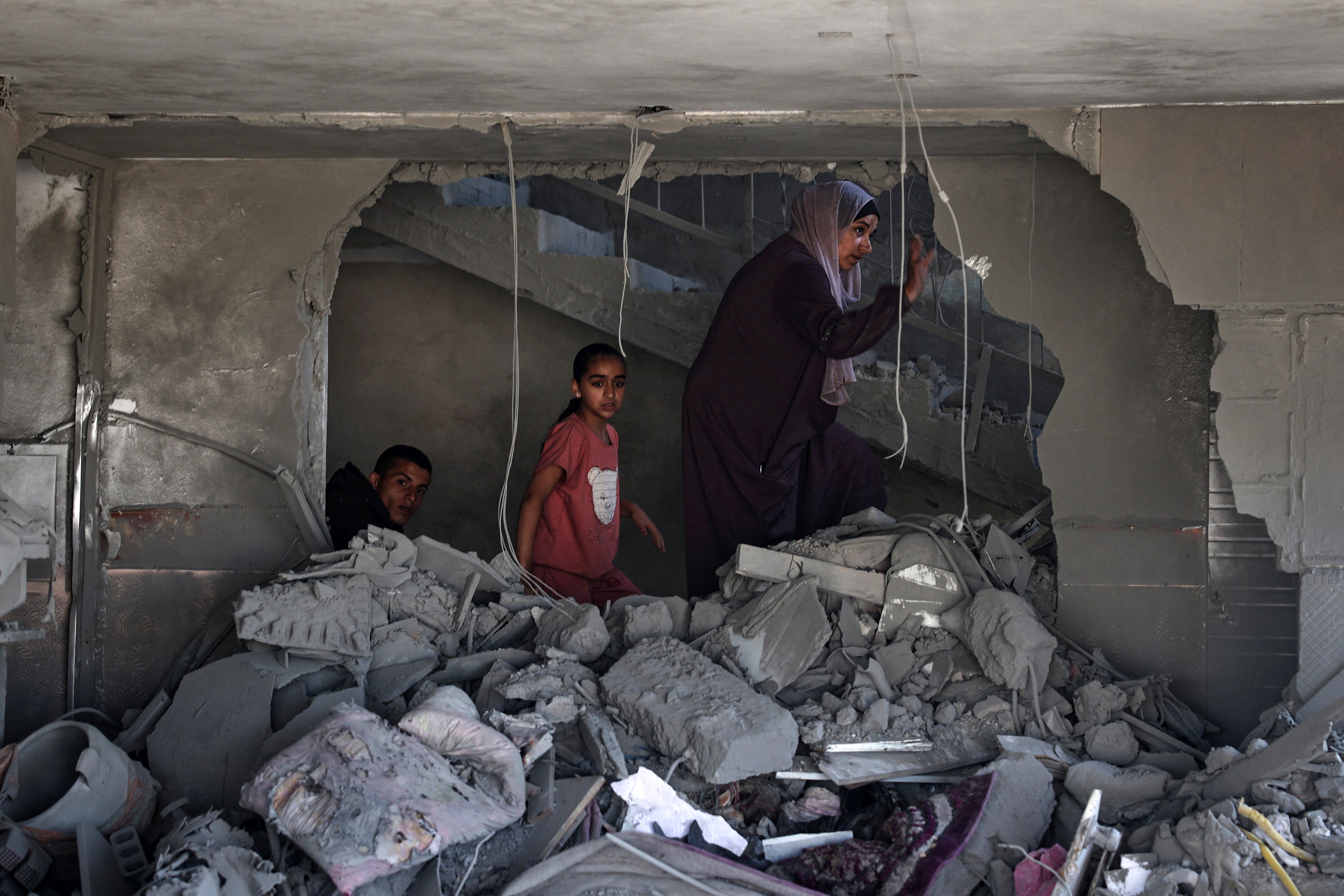 A Palestinian woman and children check the rubble of a building hit by overnight Israeli bombing in Rafah in the southern Gaza Strip on Saturday