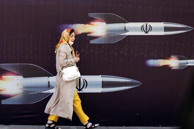 An Iranian woman walks past a huge anti-Israeli banner carrying pictures of missiles, in Tehran, Iran, 19 April 2024. Iranian state media reported that three aerial objects were destroyed by air defense systems over the central city of Isfahan early morning on 19 April. The explosions come after a drone and missile attack carried by Iran's Islamic Revolutionary Guards Corps (IRGC) towards Israel on 13 April, following an airstrike on the Iranian embassy in Syria which Iran claimed was conducted by Israel