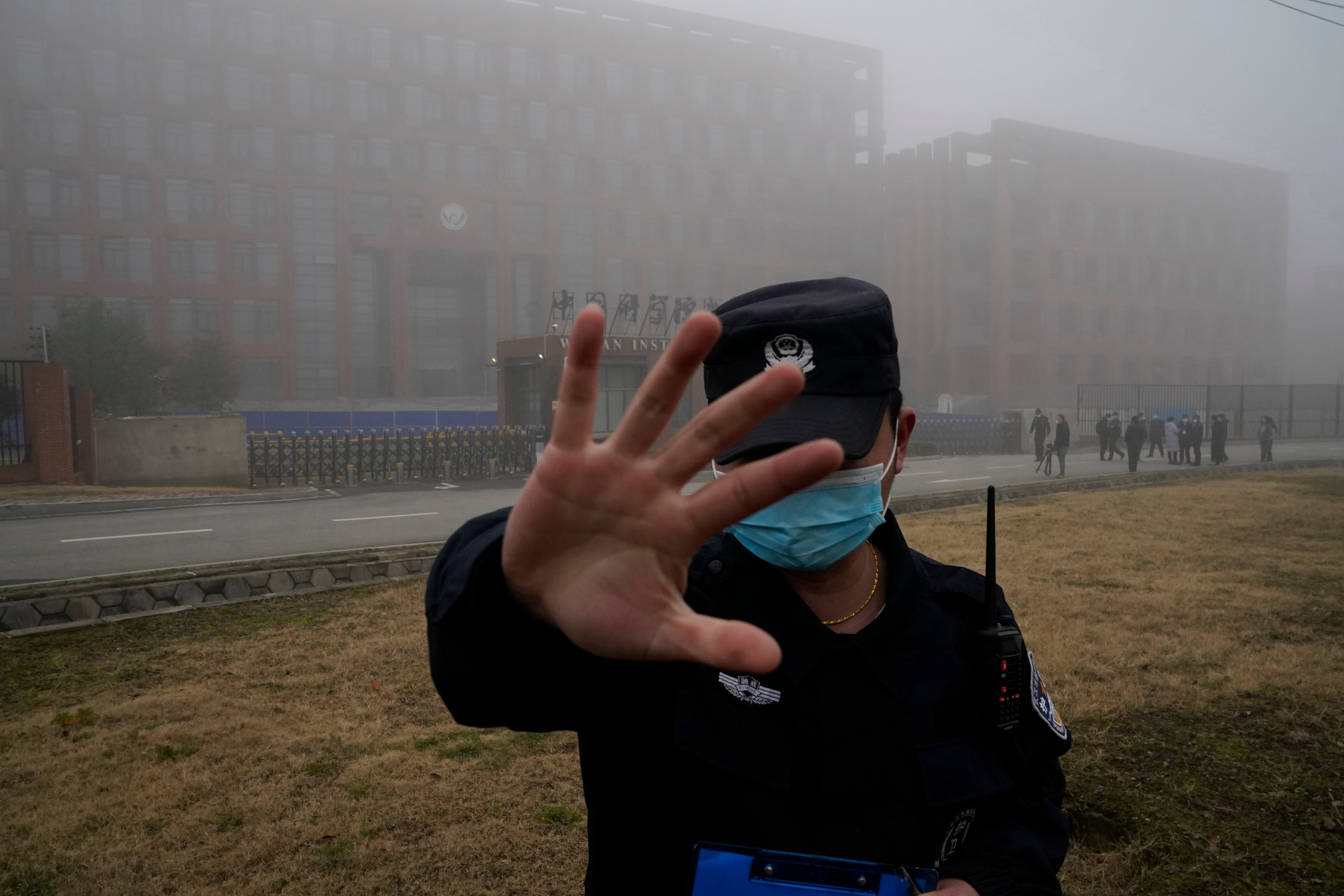 A security guard keeps journalists away from the Wuhan Institute of Virology