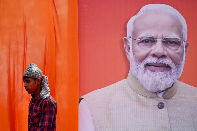 <p>A worker walks past a hoarding of Narendra Modi ahead of India’s national elections</p>