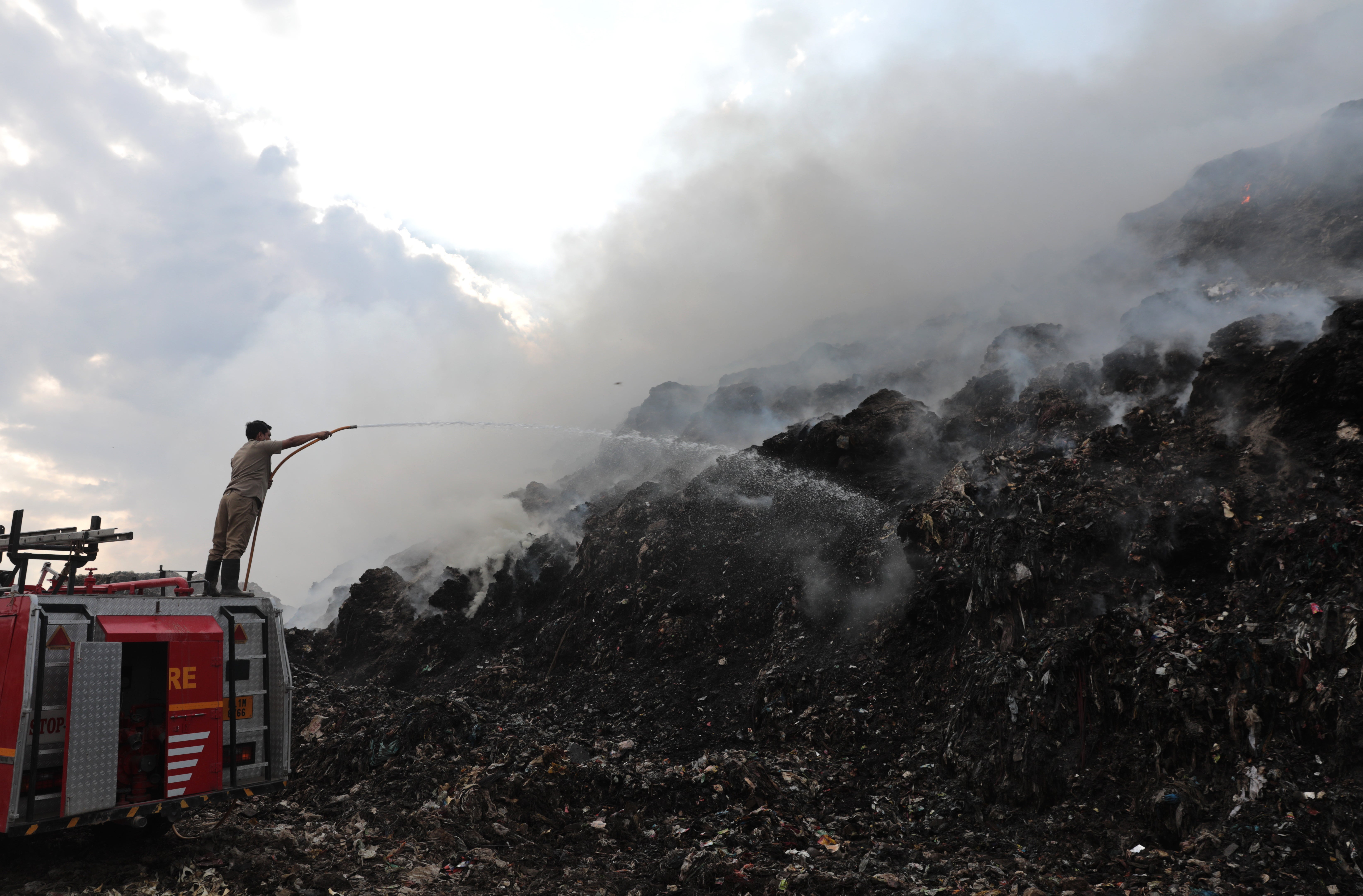 Indian firefighters work to extinguish the fire at the Ghazipur landfill