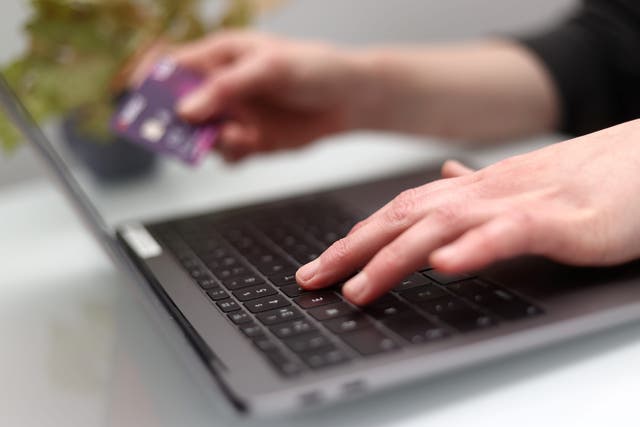 A woman using a laptop as she holds a bank card (PA)