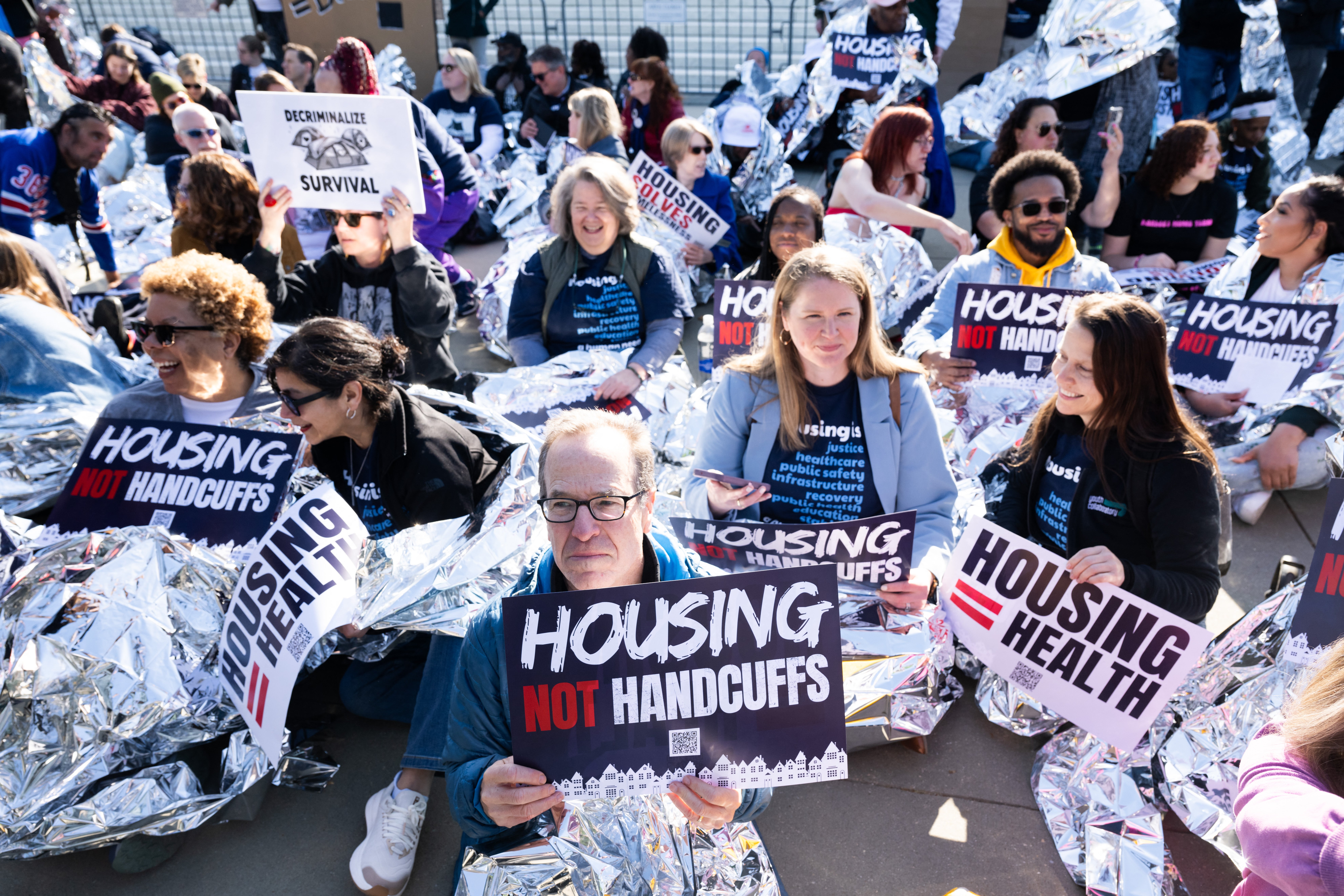 Homelessness activists hold signs and use reflective blankets during a protest outside the US Supreme Court in Washington, DC, April 22, 2024