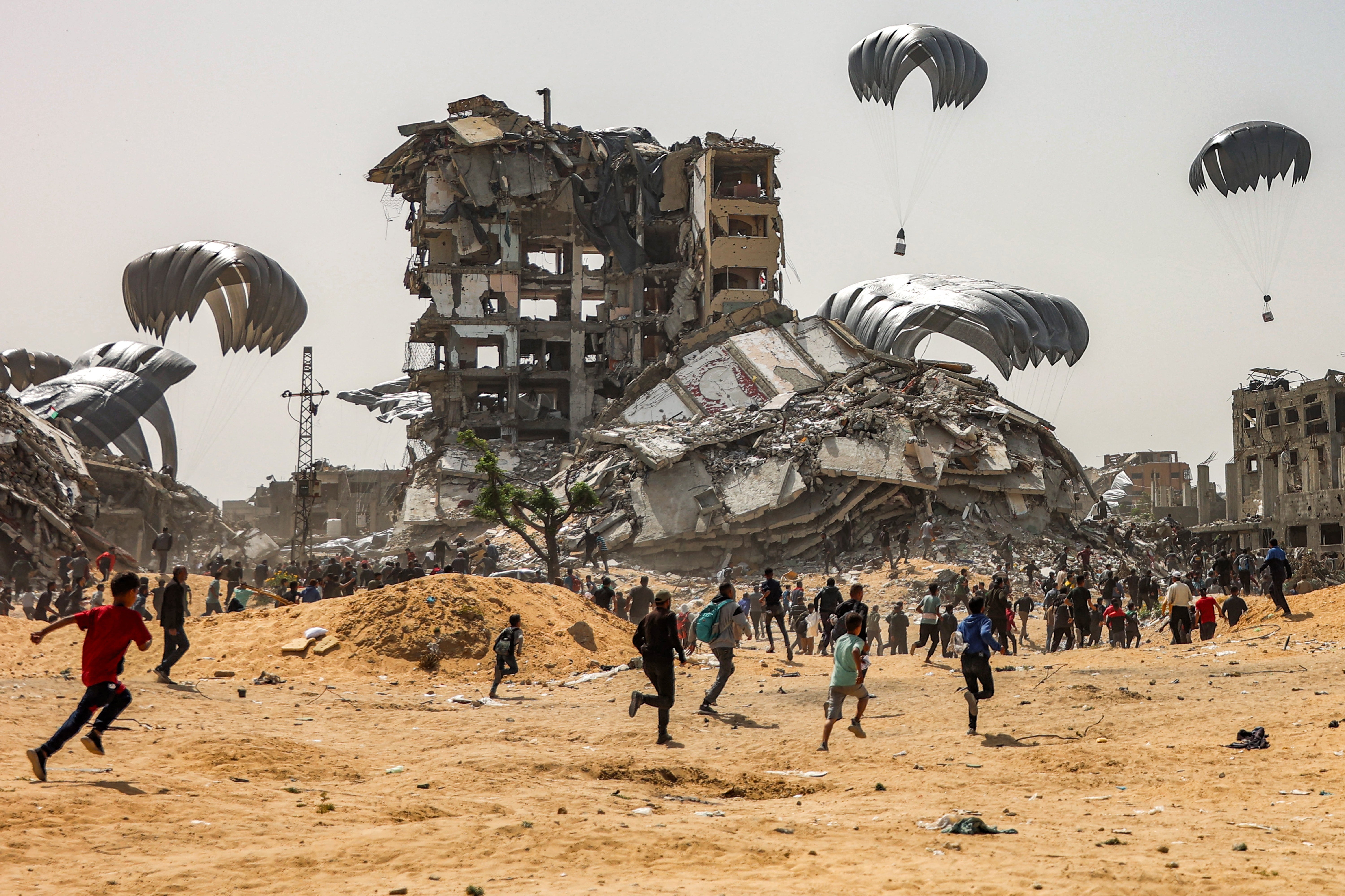 People rush to landing humanitarian aid packages dropped over the northern Gaza Strip on 23 April, 2024