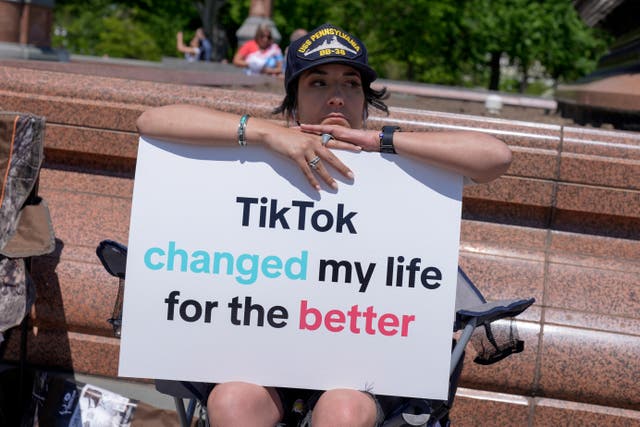 <p>A TikTok content creator sits outside the US Capitol on Tuesday 23 April while senators considered legislation that would force TikTok's China-based parent company to sell the social media platform under the threat of a ban</p>
