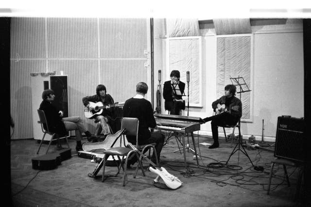 <p>George Harrison playing the guitar during a Beatles studio session</p>