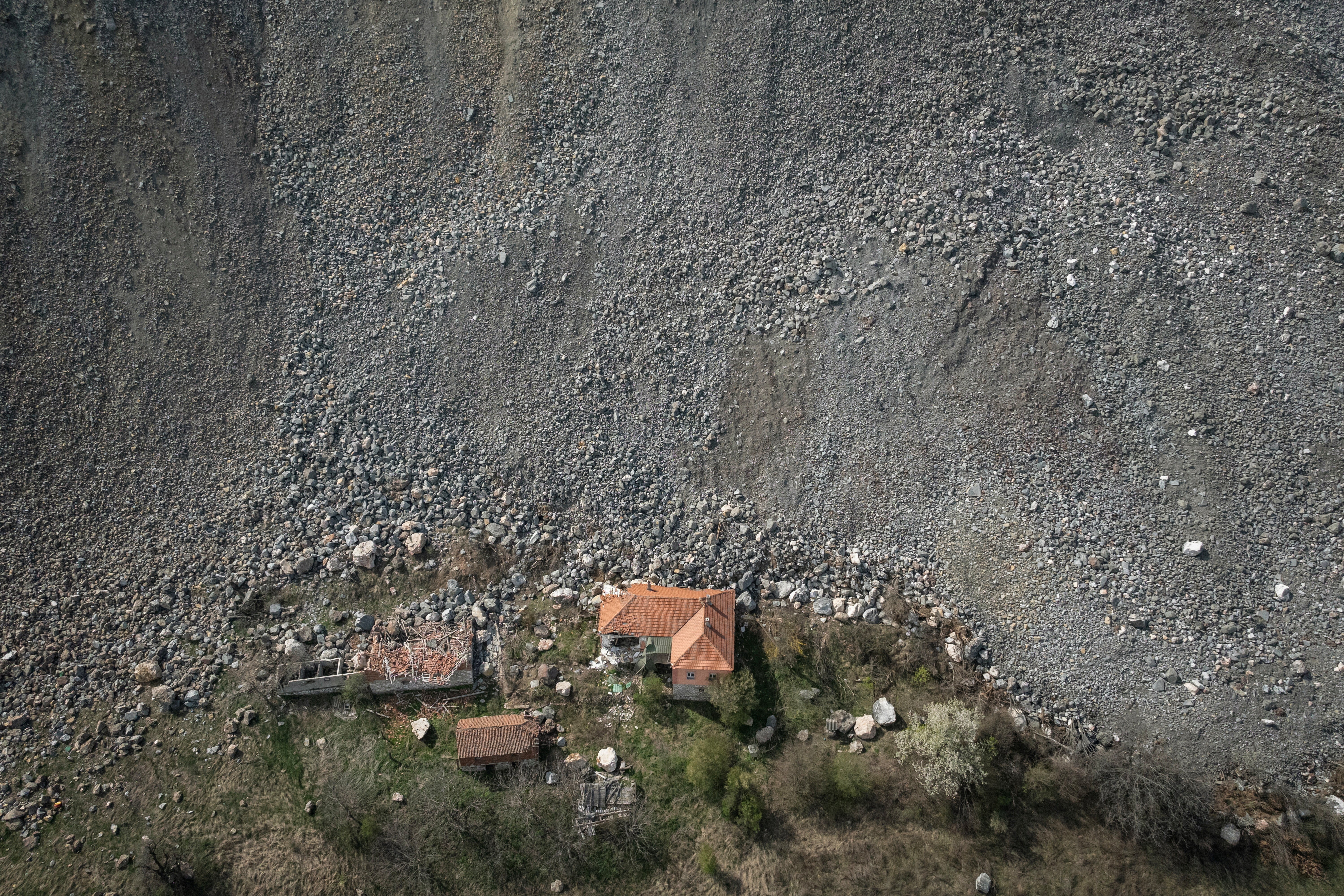 A destroyed house is seen near an open-pit copper mine