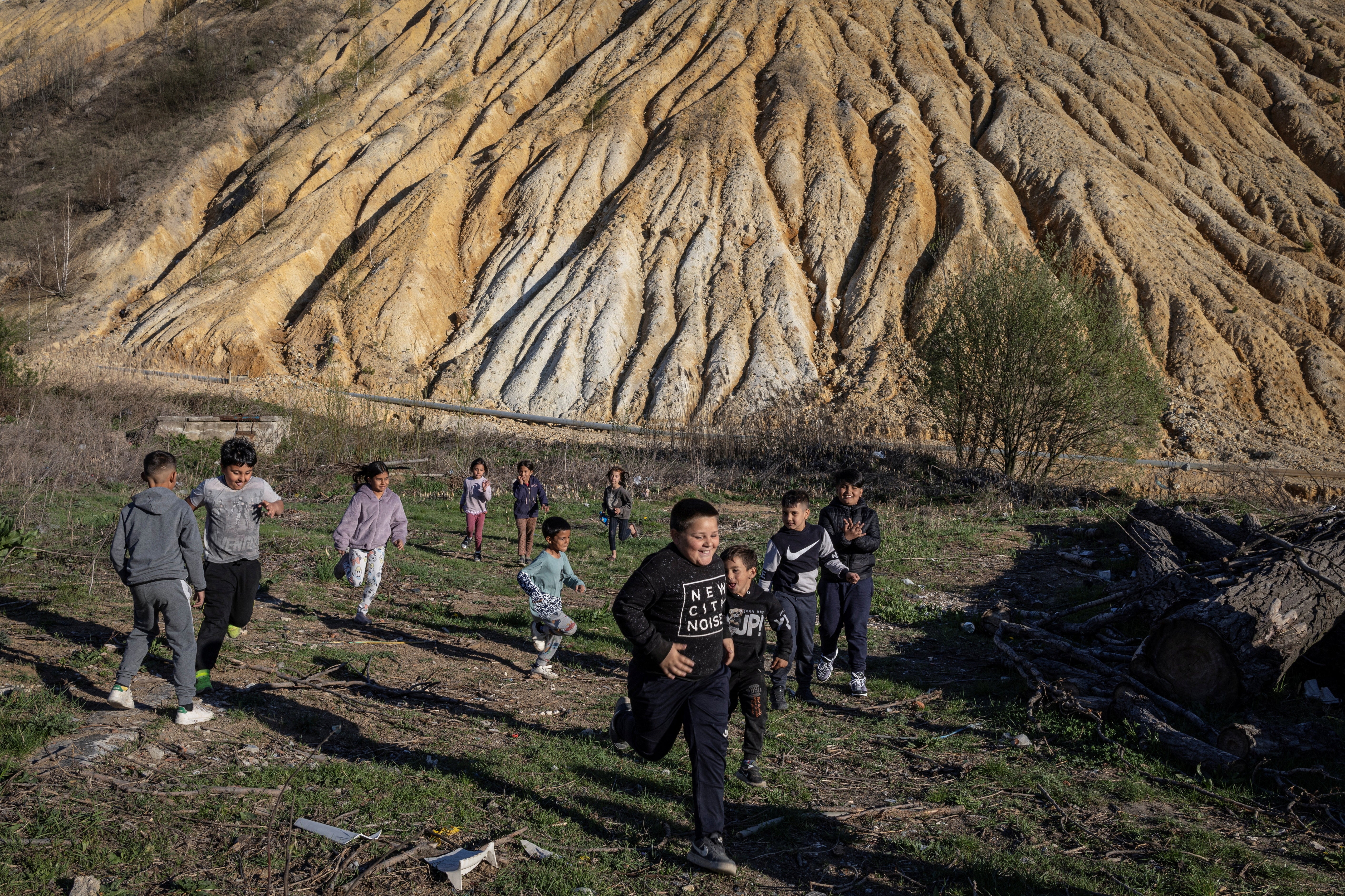 Children play in front of tailings at the Zmajevo settlement